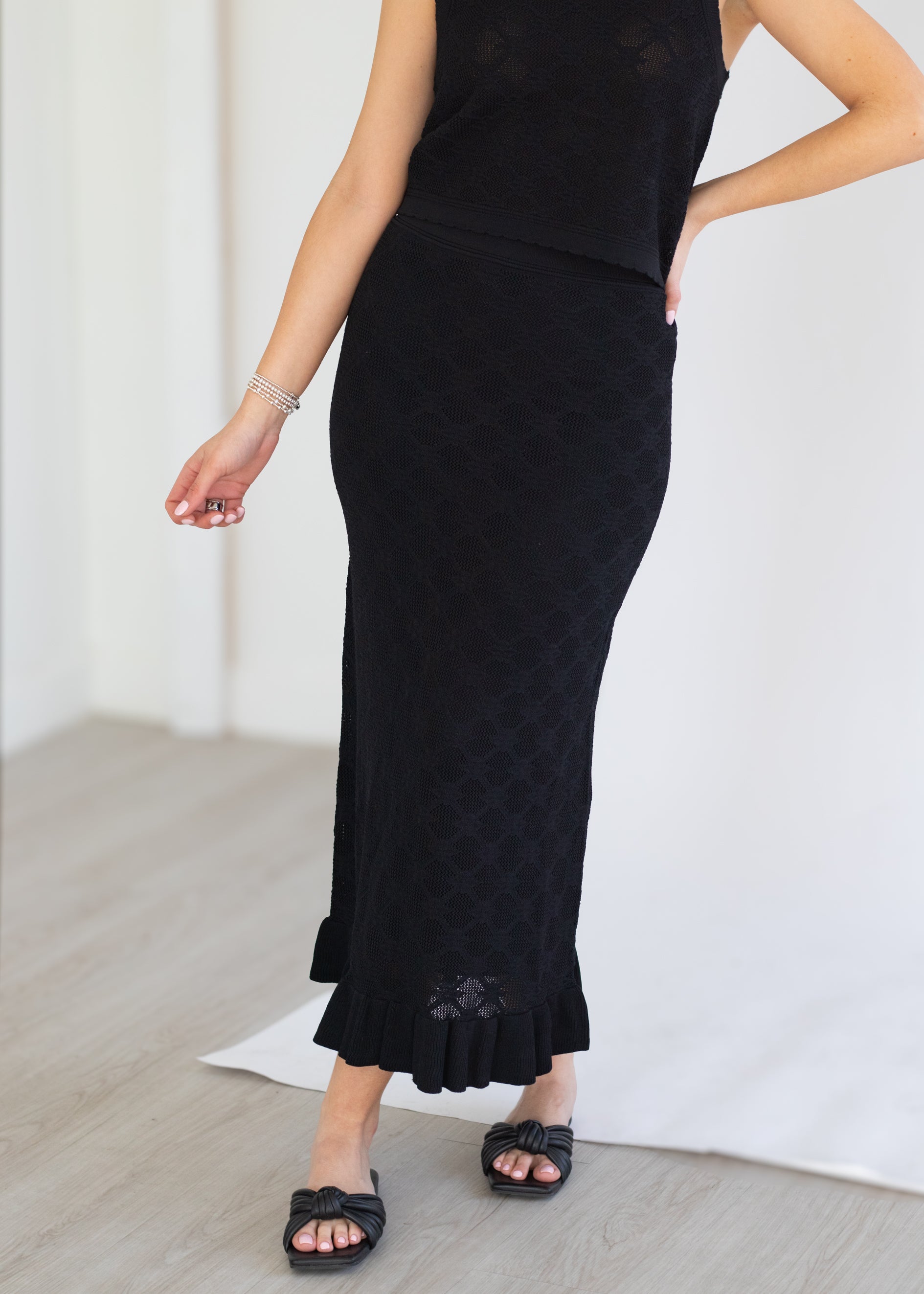 Person wearing a black dress with a textured pattern on a light background