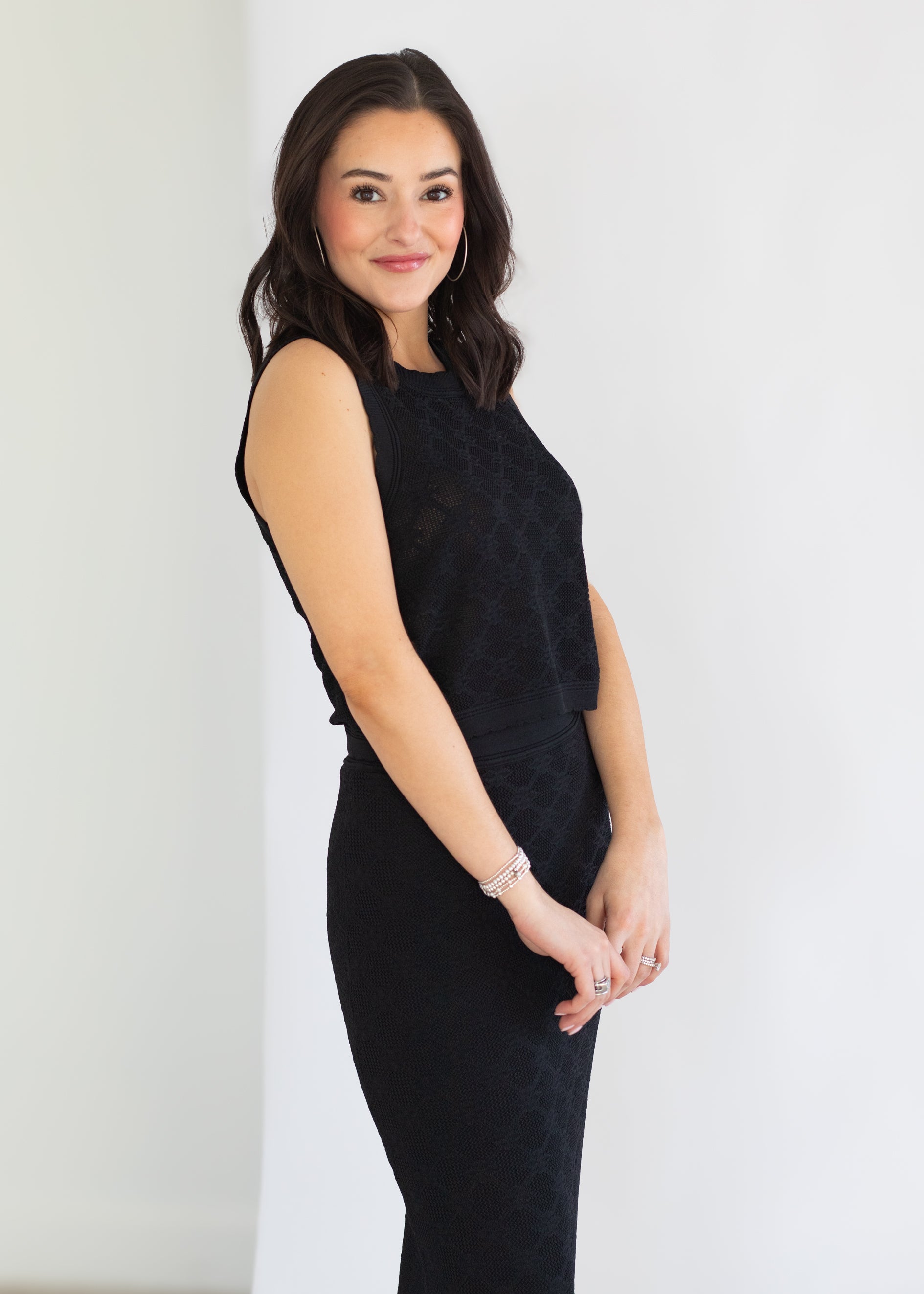 Woman wearing a black sleeveless dress against a white background