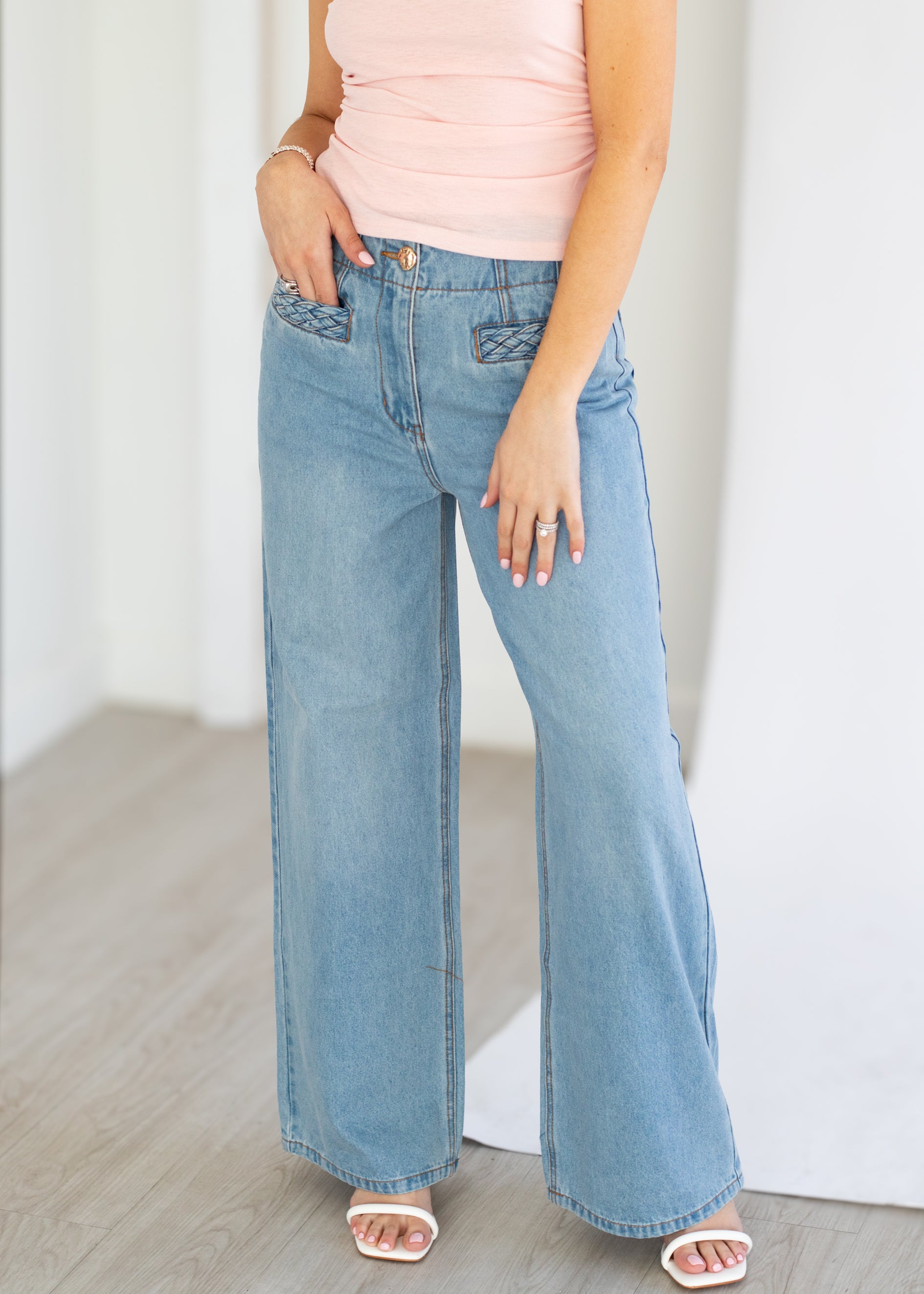 Person wearing light blue wide-leg jeans and a pink top against a white background