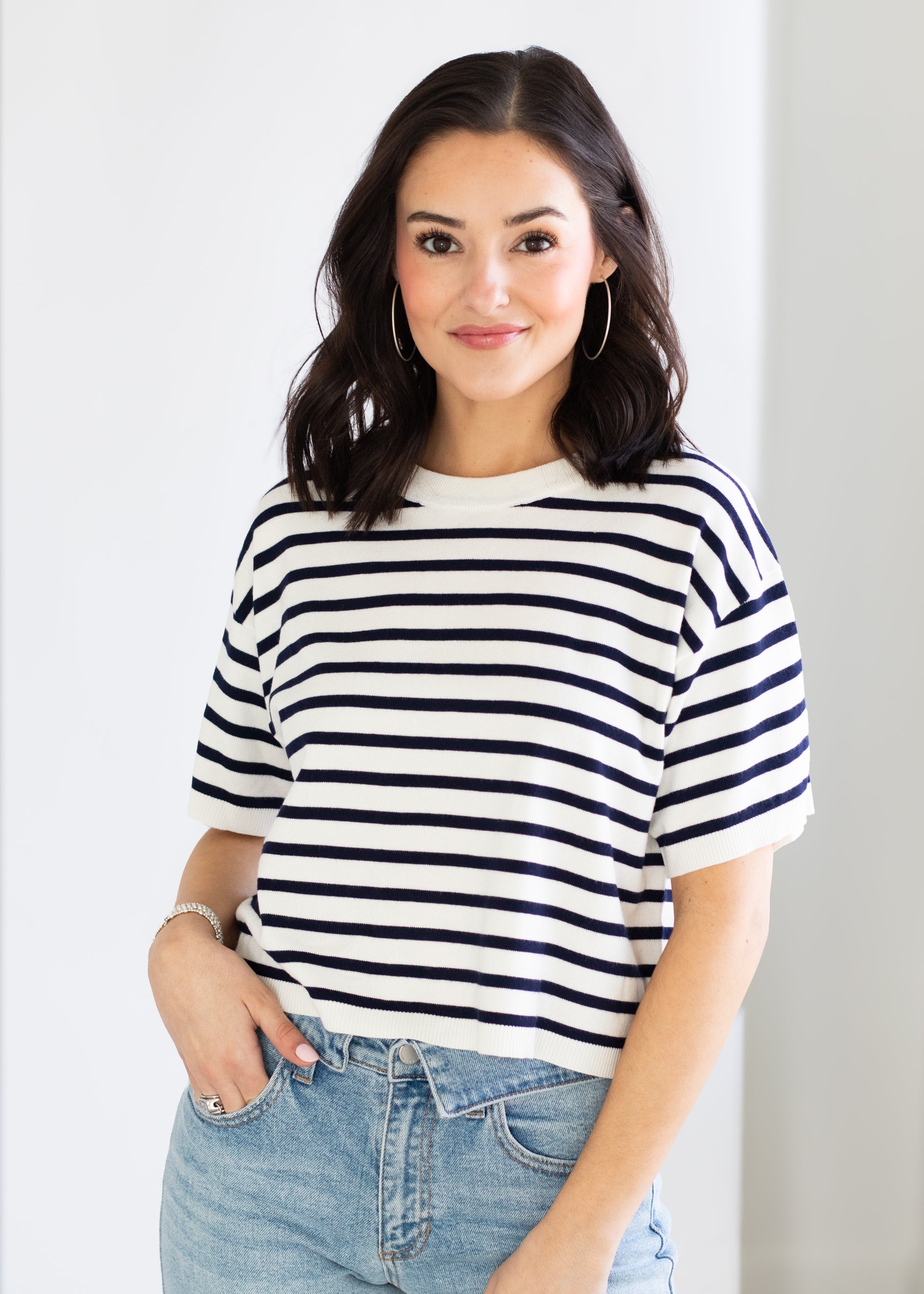 Woman wearing a navy and white striped shirt with blue jeans against a white background