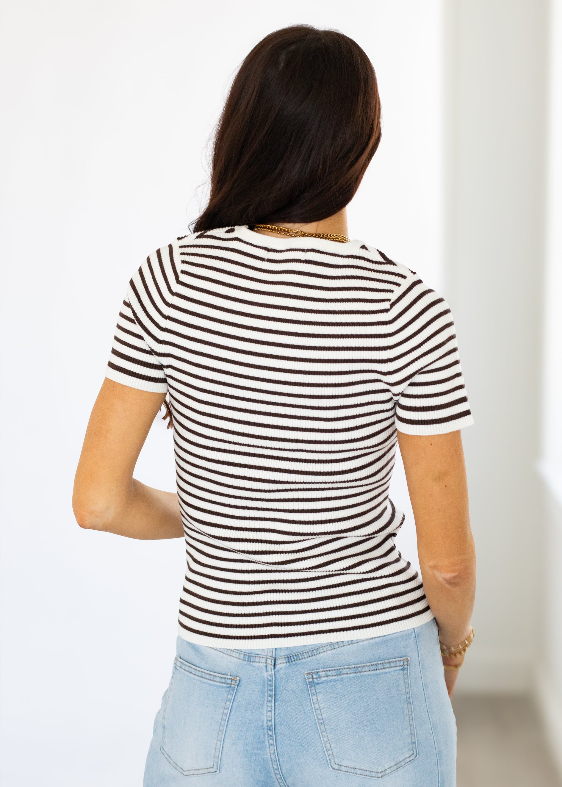 Person wearing a black and white striped shirt with a plain background