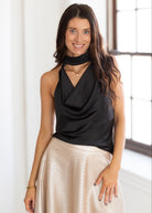 Woman wearing a black top and beige skirt indoors