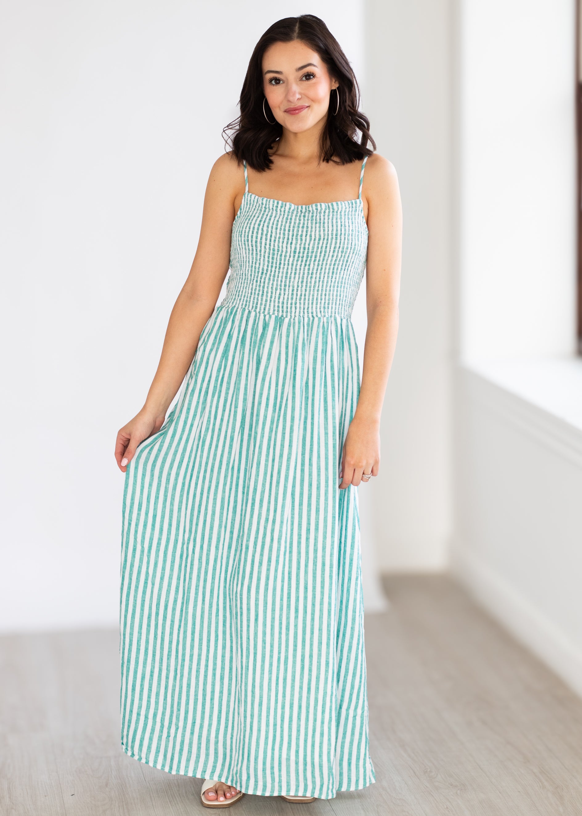 Woman wearing a green and white striped dress in a minimal indoor setting