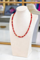 Red beaded necklace on a white mannequin bust with a blurred background