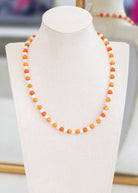 Necklace with orange beads on a white mannequin bust