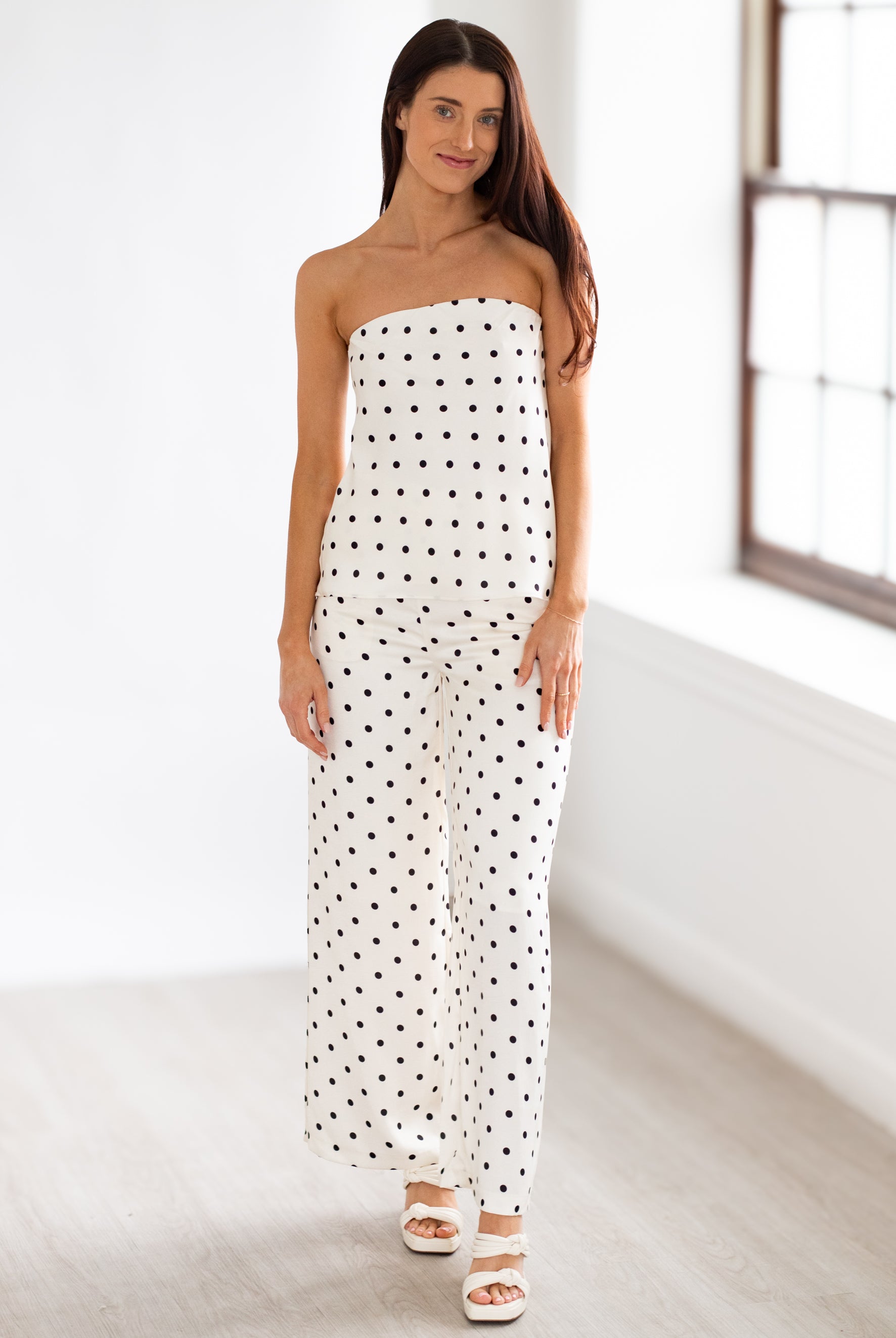 Woman wearing a strapless polka dot outfit in a minimal indoor setting