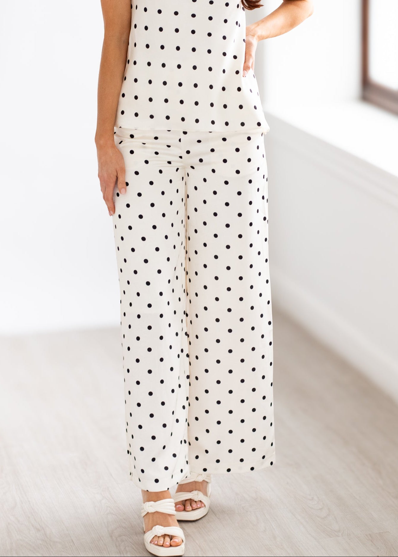 Woman wearing a strapless polka dot outfit in a minimal indoor setting