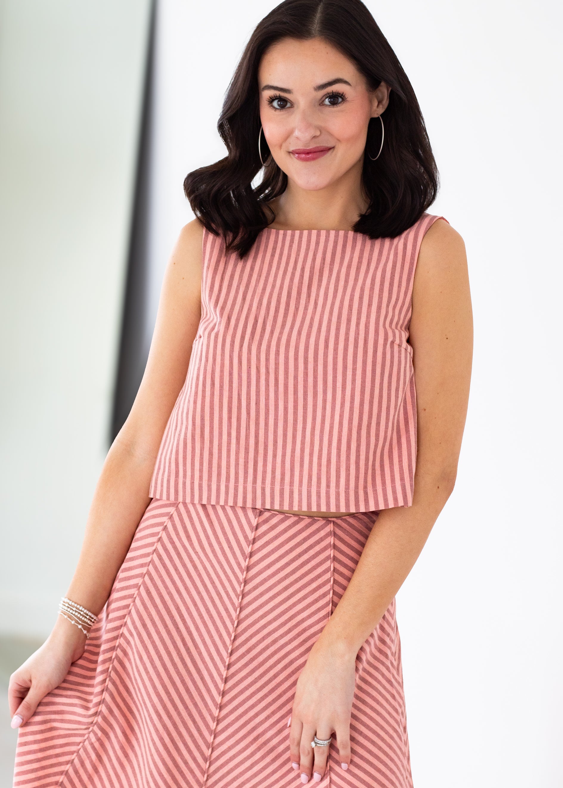 Woman wearing a pink and white striped outfit against a plain background