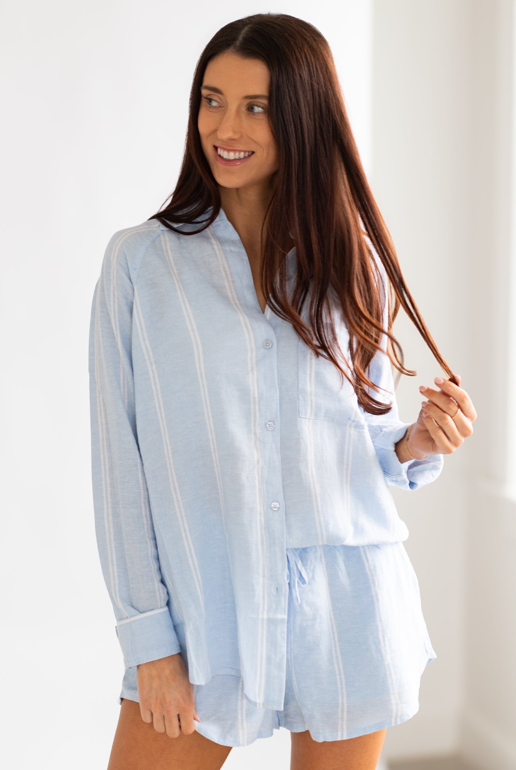 Woman wearing a light blue striped shirt against a white background