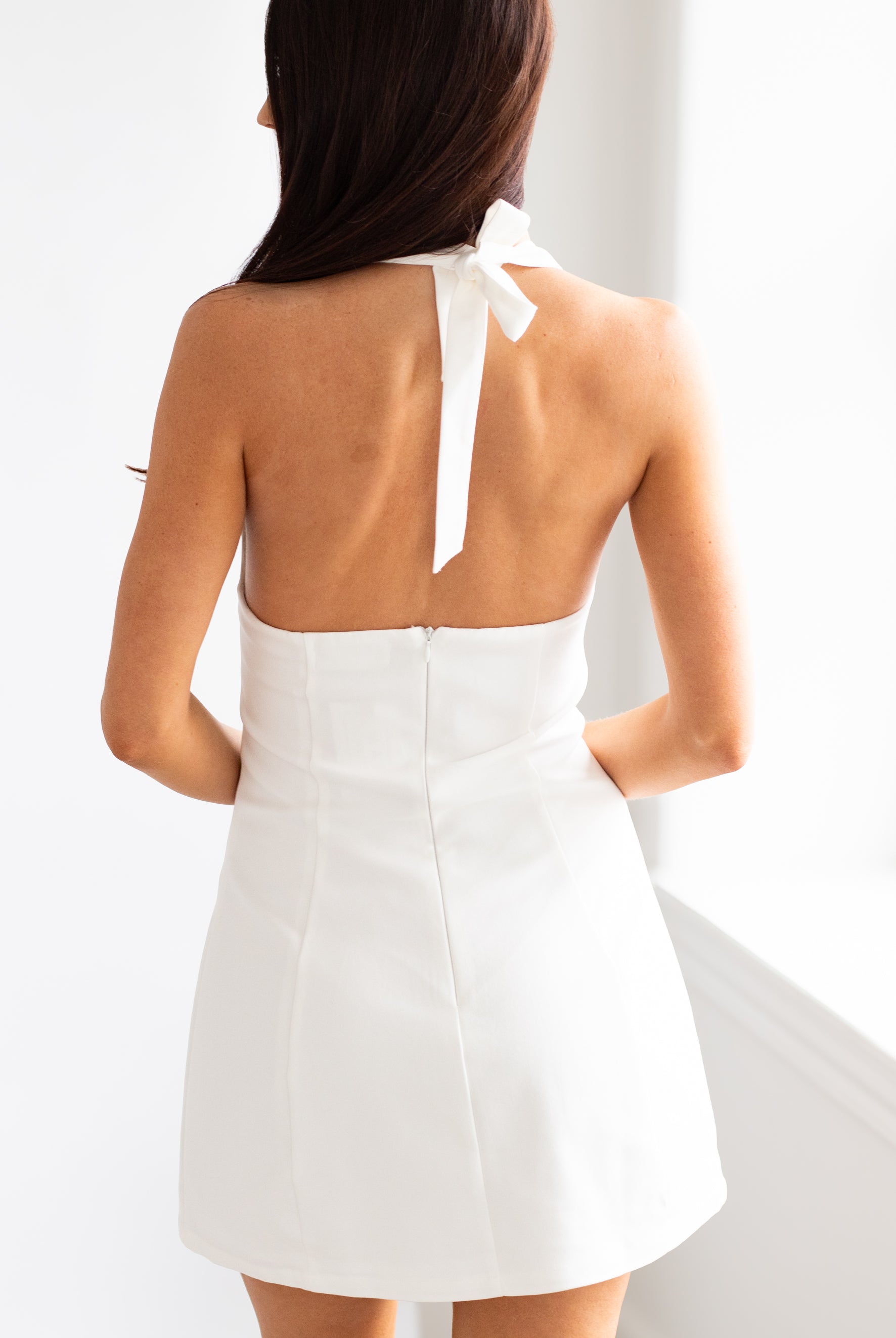 White dress with a bow detail on the back, worn by a person.