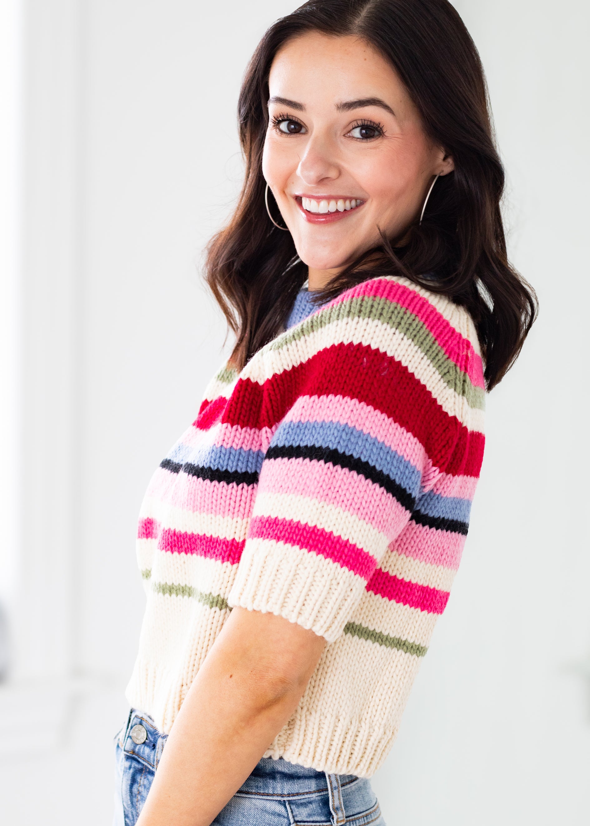 Woman wearing a colorful striped sweater against a white background