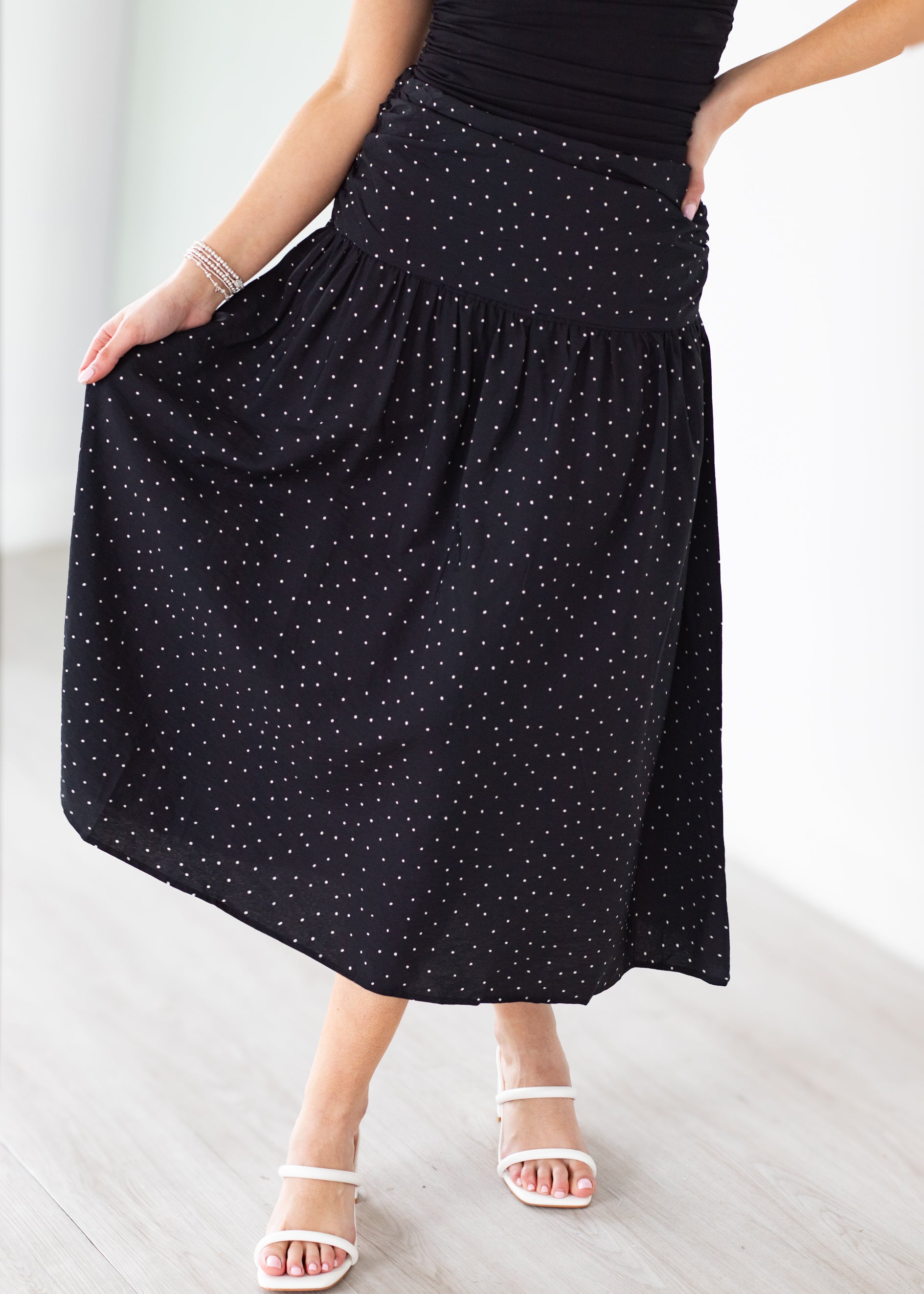 Person wearing a black polka dot skirt on a light background