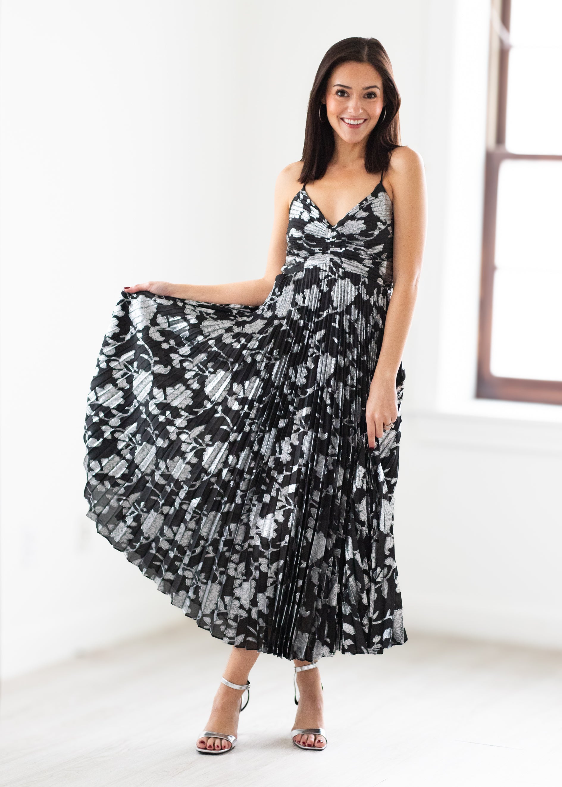 Woman wearing a black and silver floral dress in a bright room.
