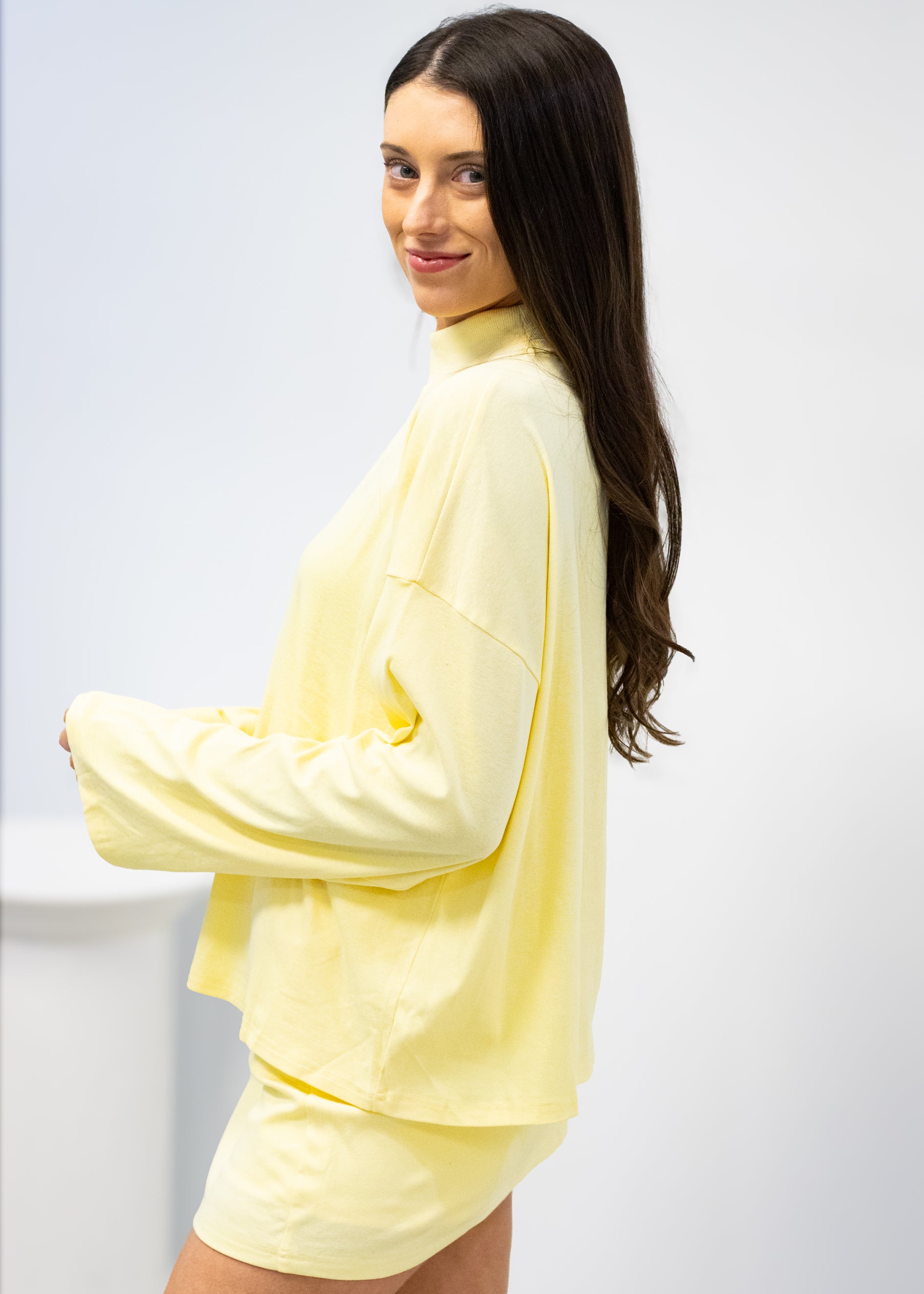 Woman wearing a light yellow outfit against a white background