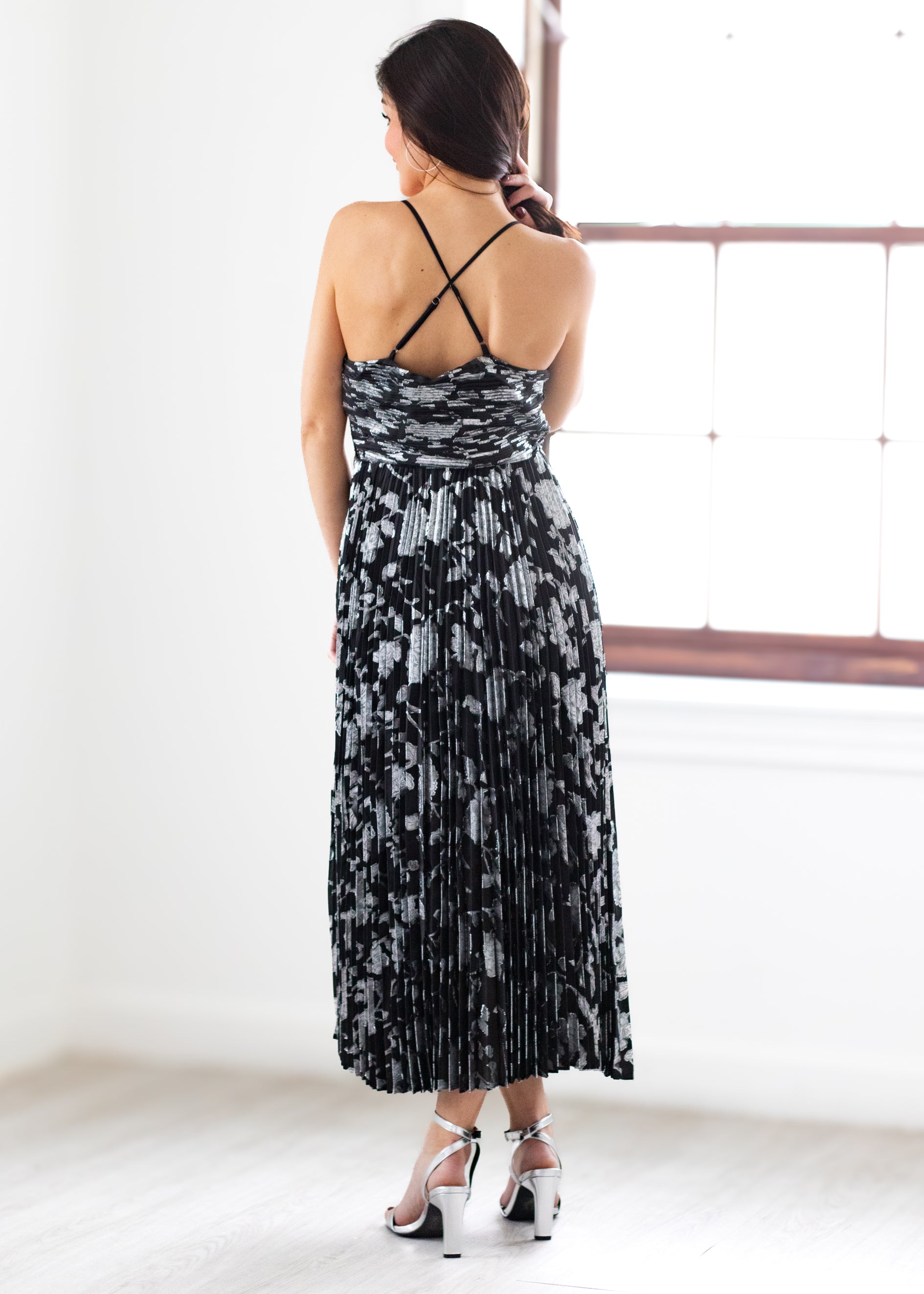 Woman wearing a black and silver patterned dress in a bright room.