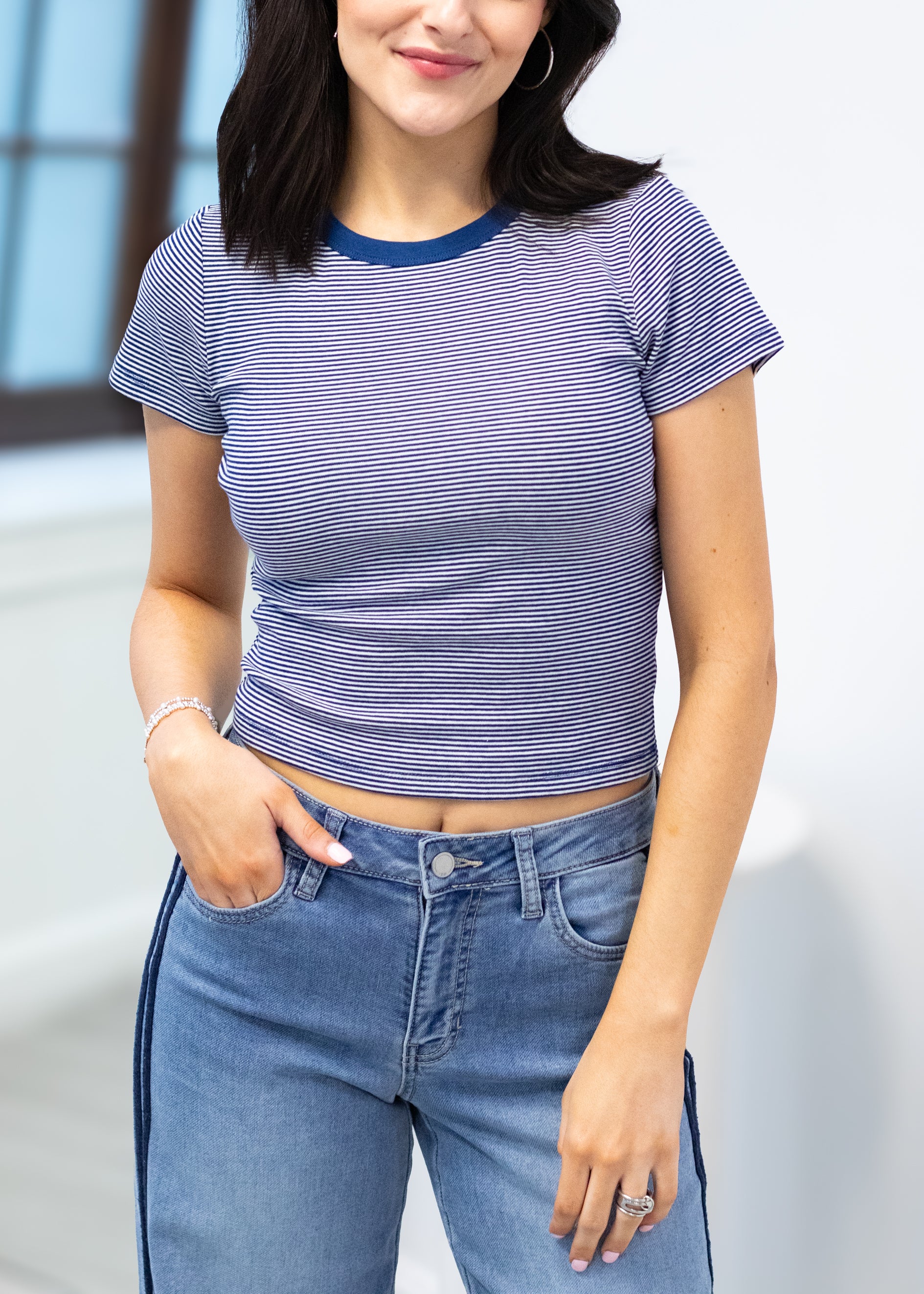 Person wearing a striped crop top and jeans with a blurred background
