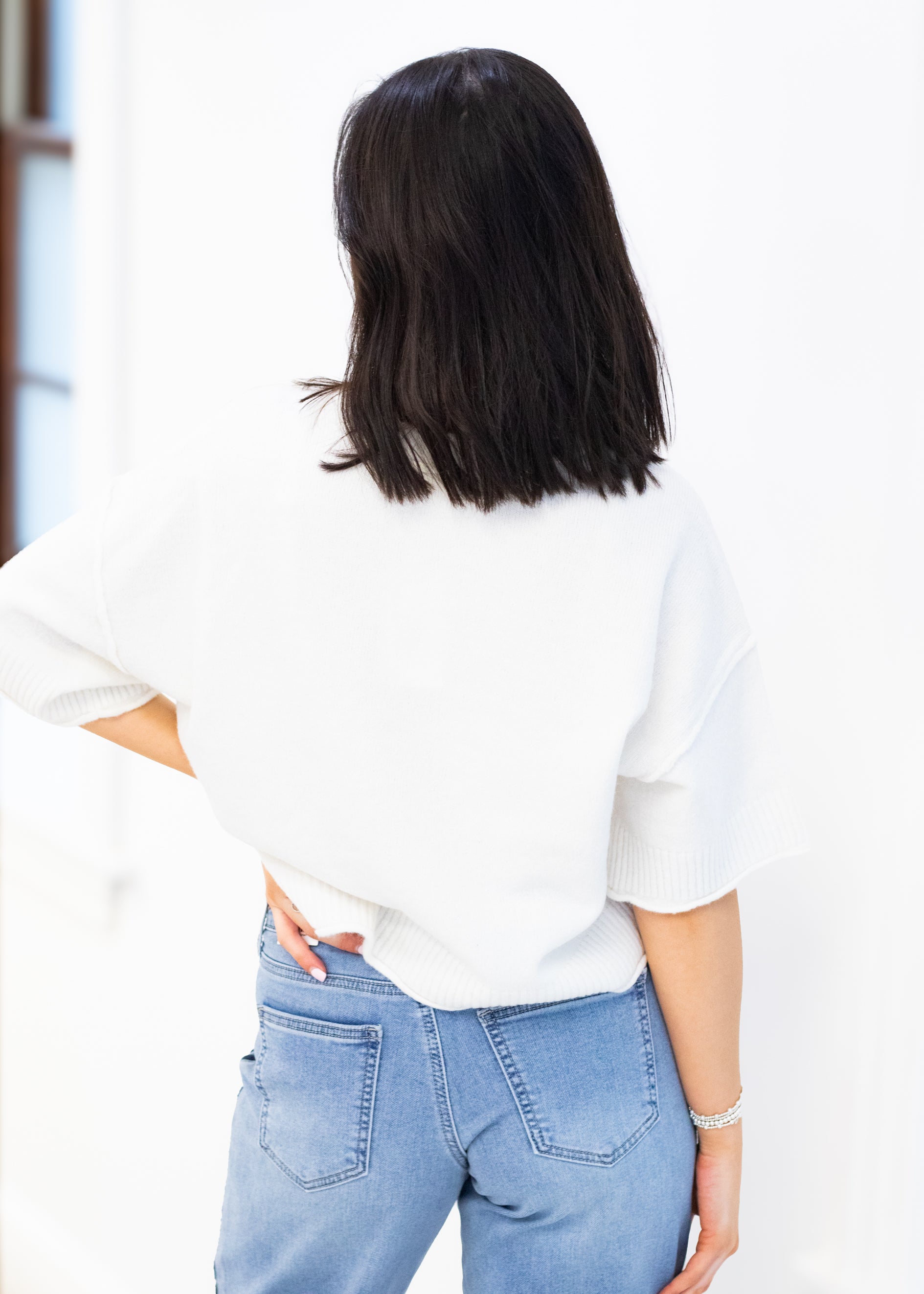 Person wearing a white blouse and blue jeans with a blurred background