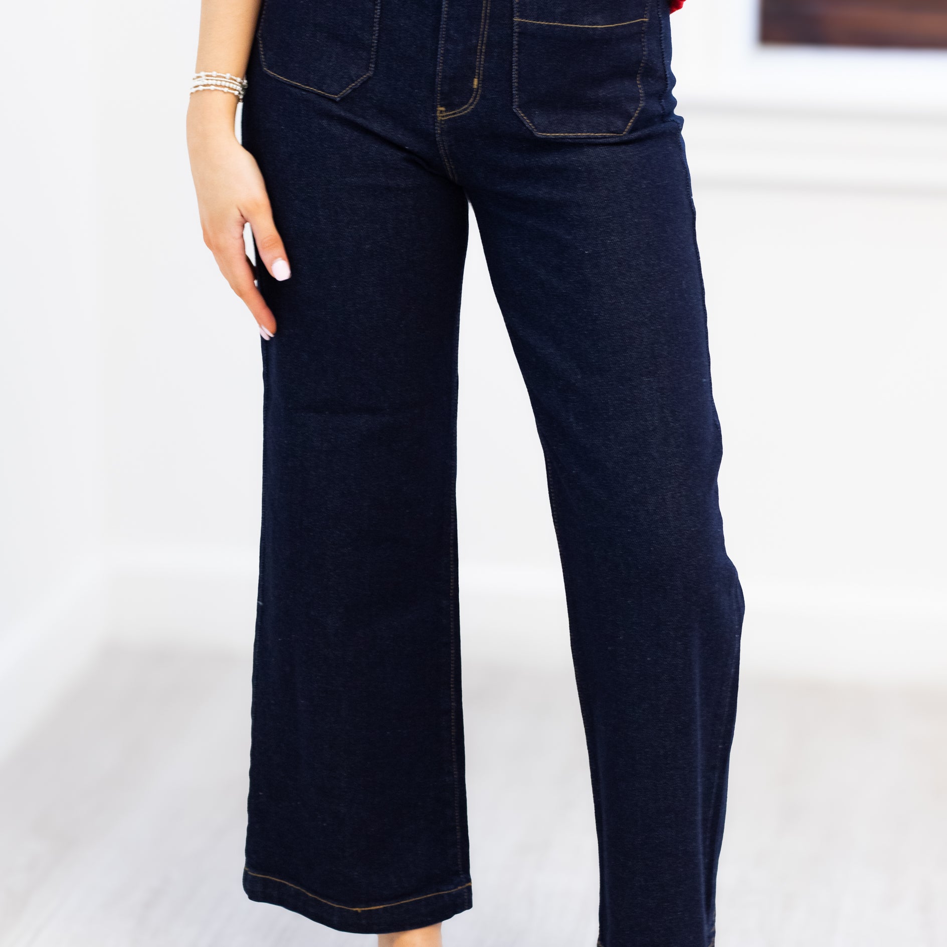 Person wearing dark blue jeans and a red top on a light background