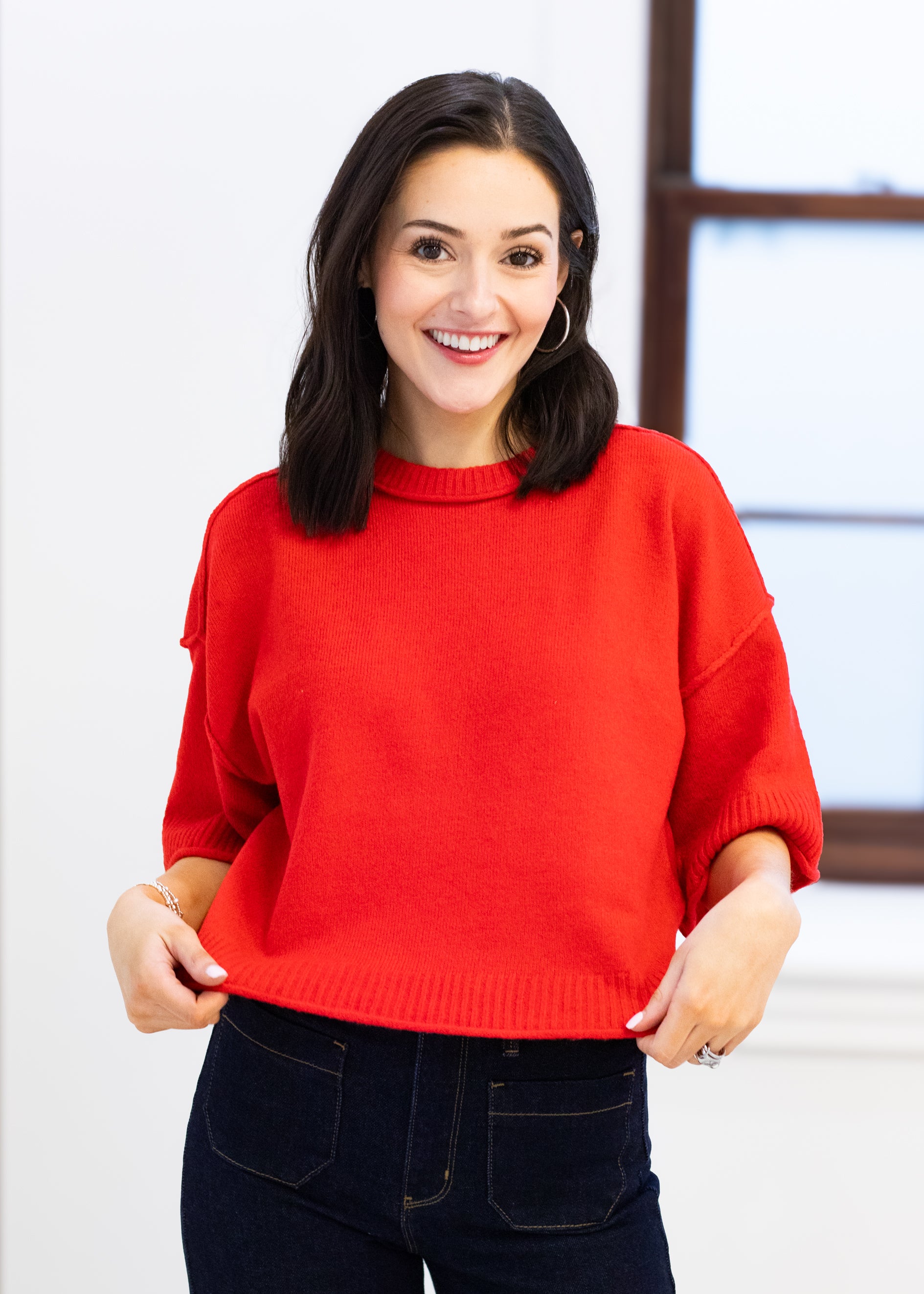 Woman wearing a red sweater in an indoor setting