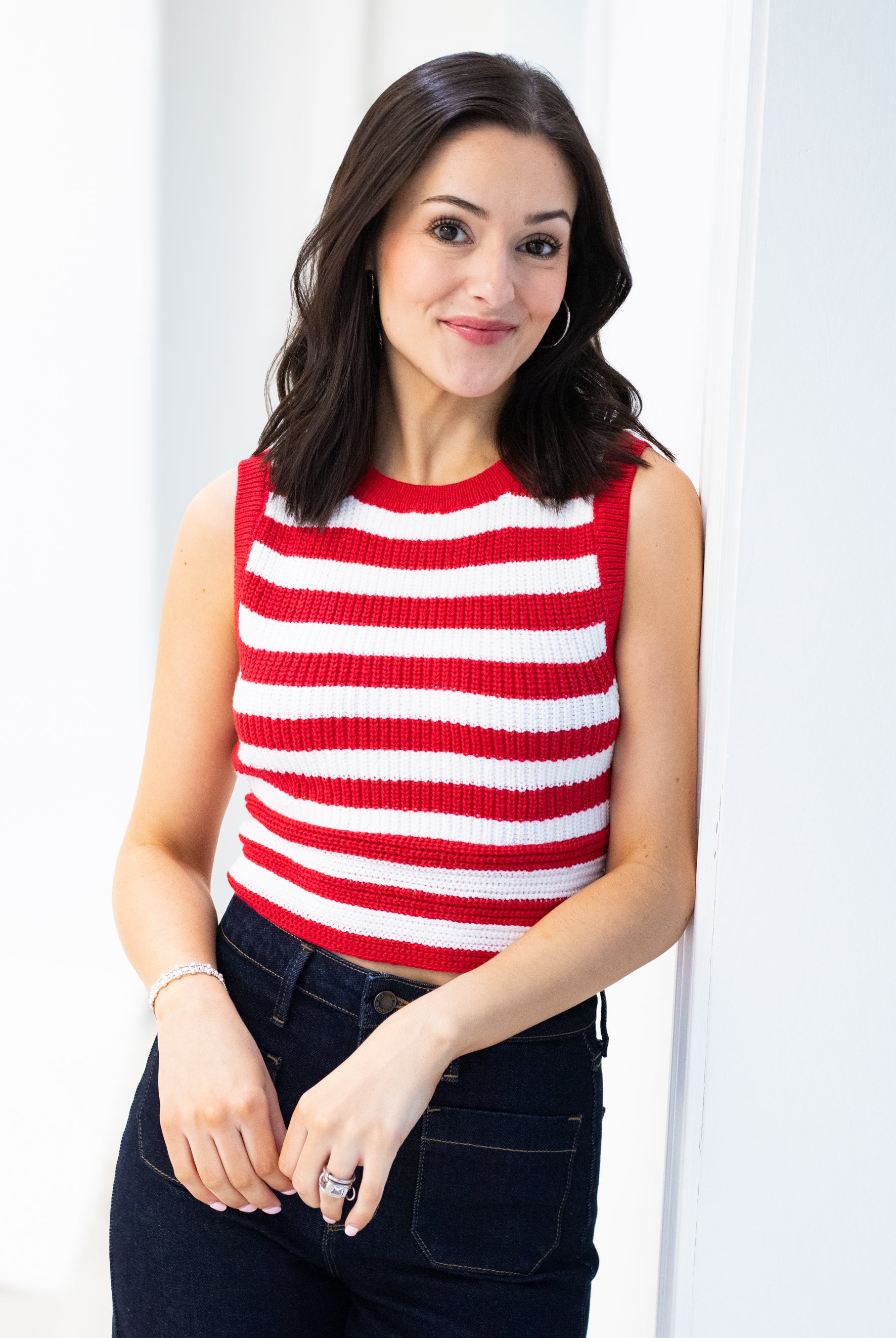 Woman wearing a red and white striped sleeveless top against a white background