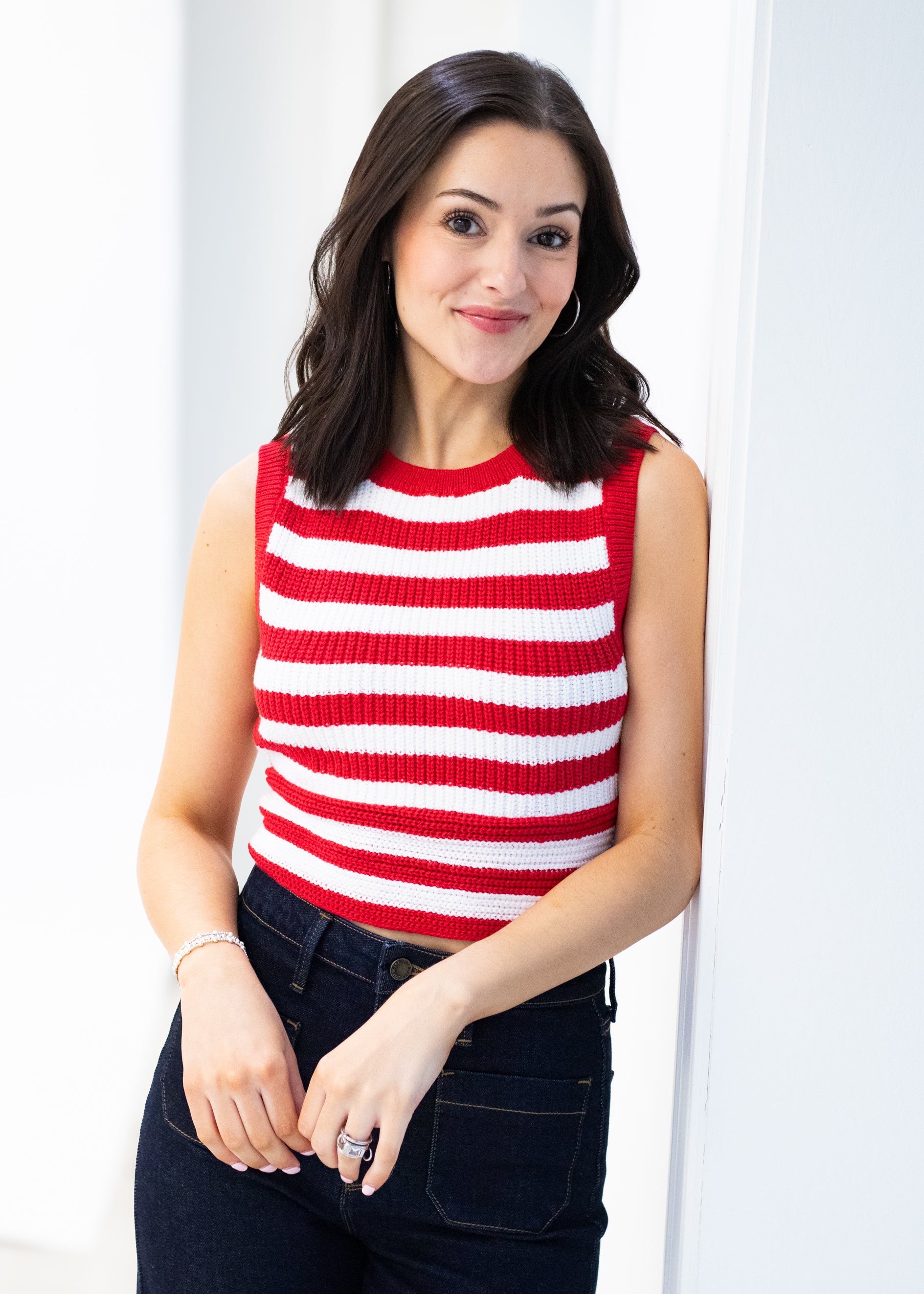 Woman wearing a red and white striped sleeveless top against a white background