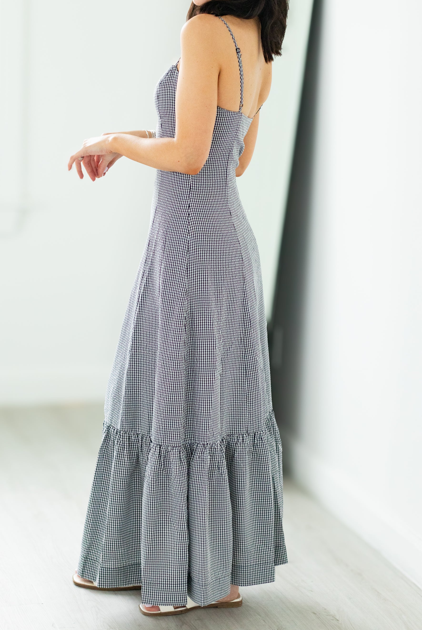 Woman wearing a long, checkered dress with a white background