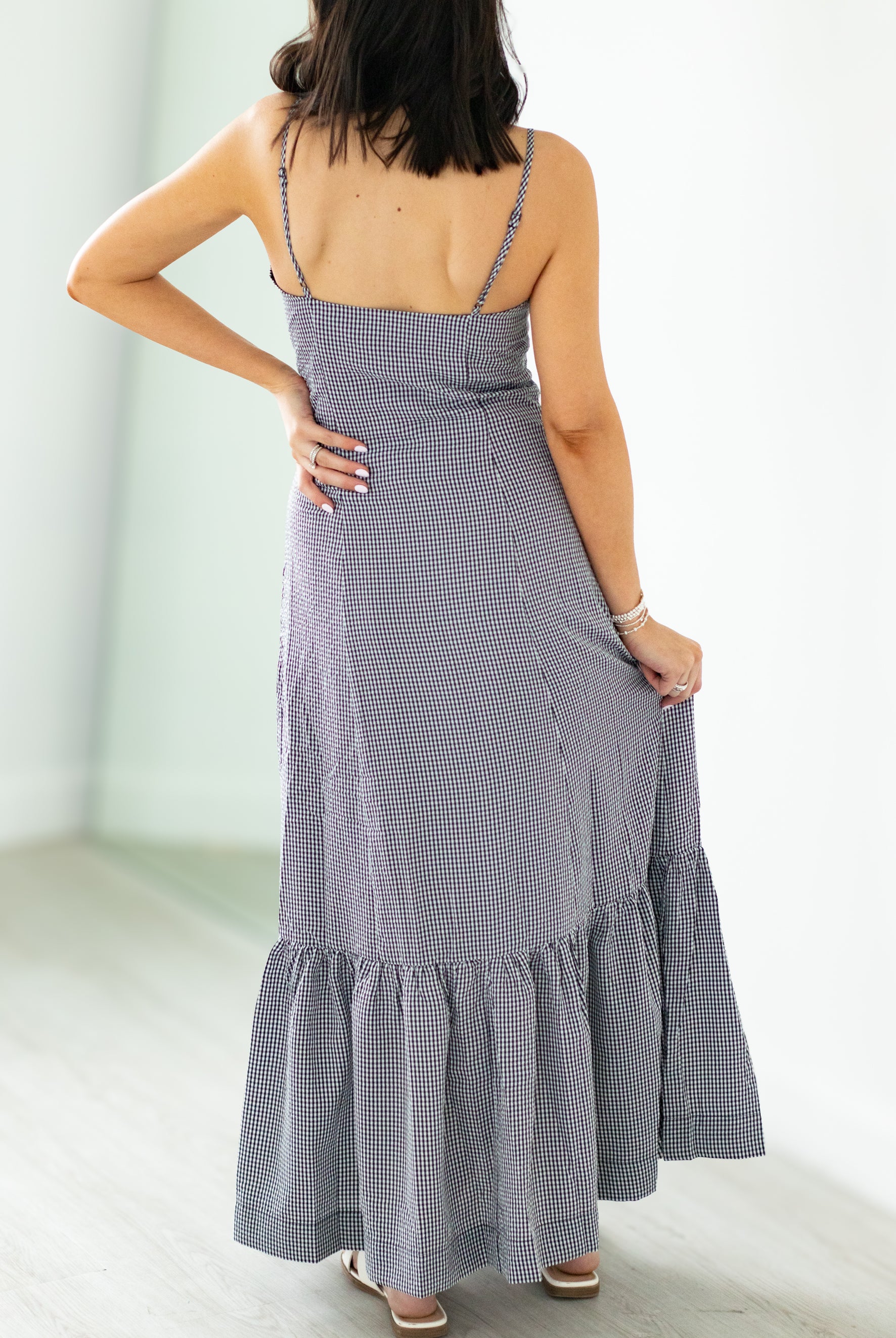 Woman wearing a gray checkered dress with a white background