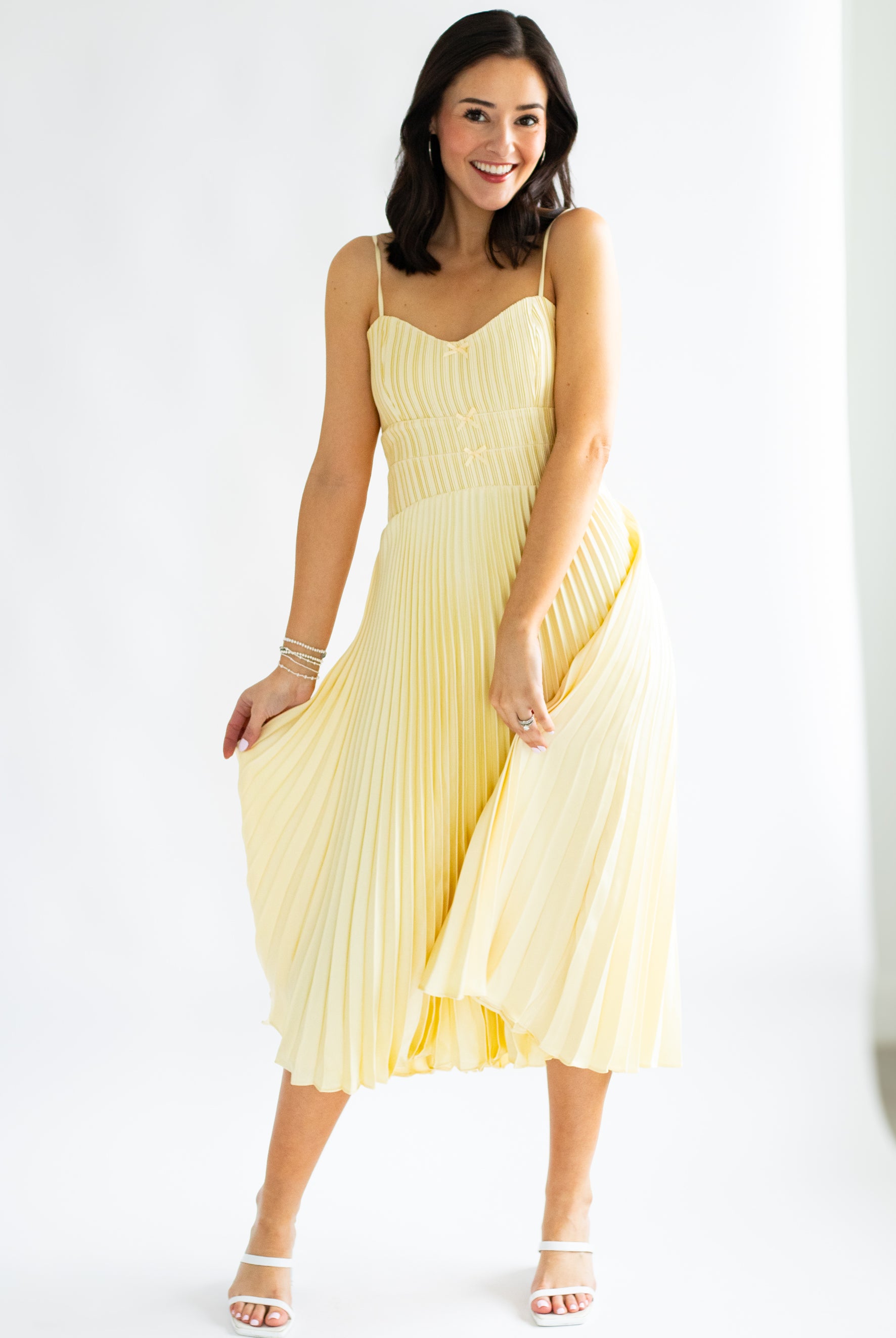 Woman wearing a yellow pleated dress on a white background