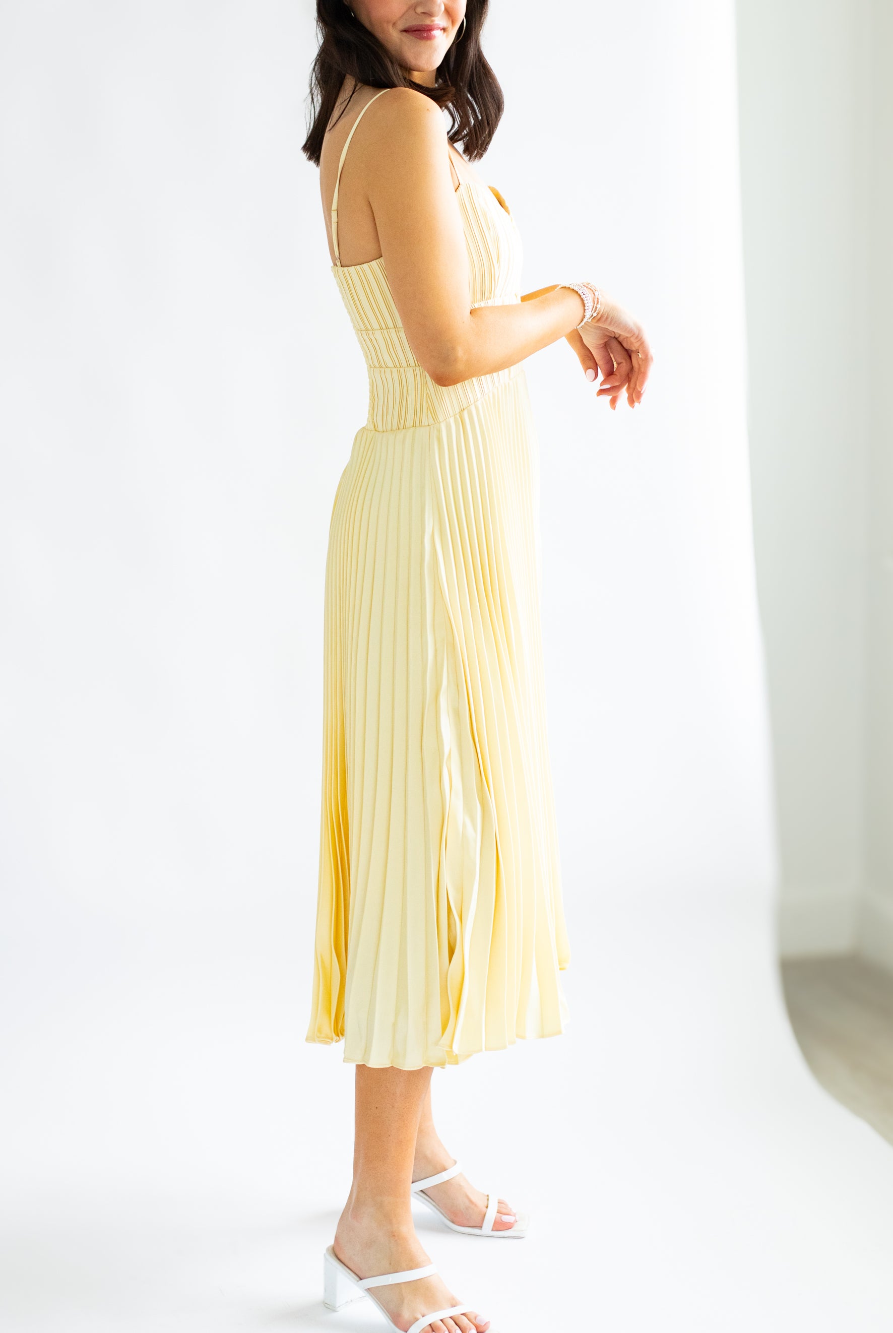 Woman wearing a yellow pleated dress against a white background