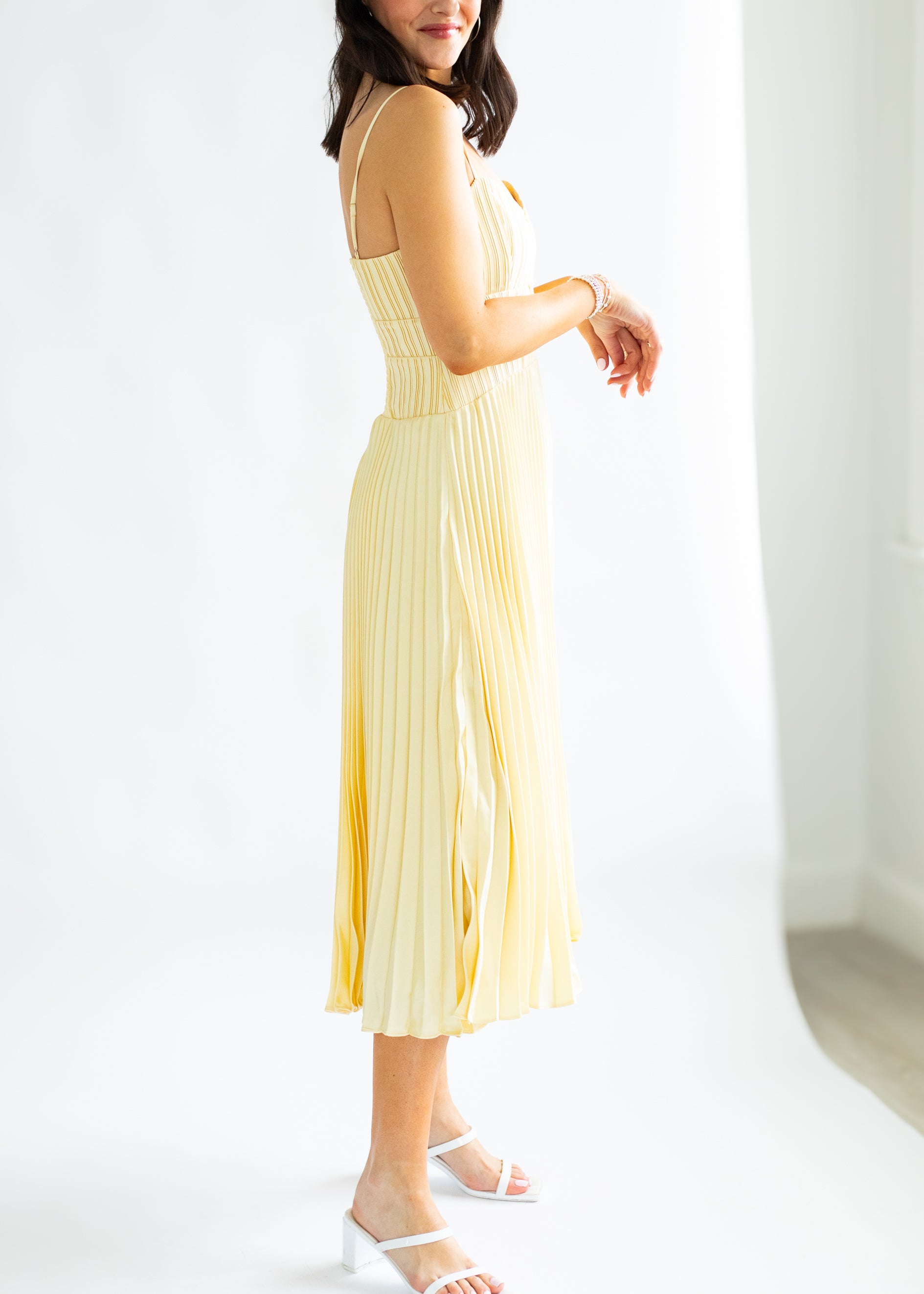 Woman wearing a yellow pleated dress against a white background