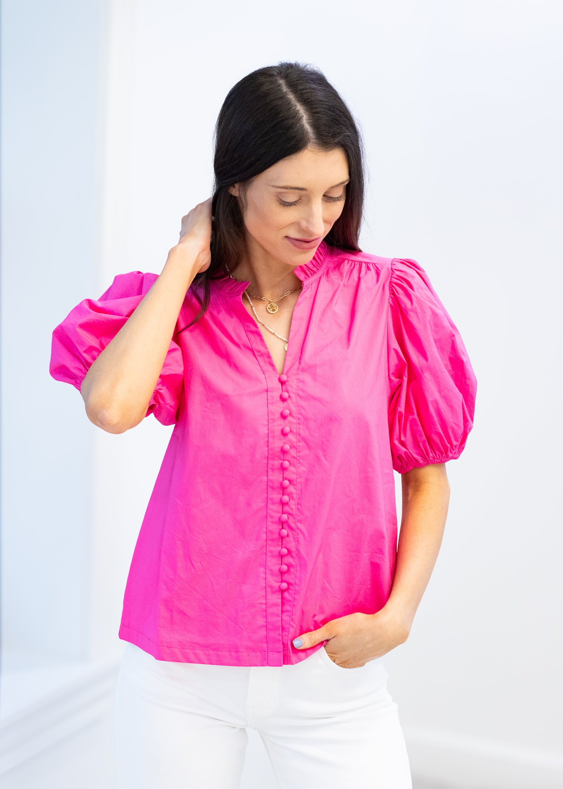 Woman wearing a bright pink blouse with puff sleeves against a light background