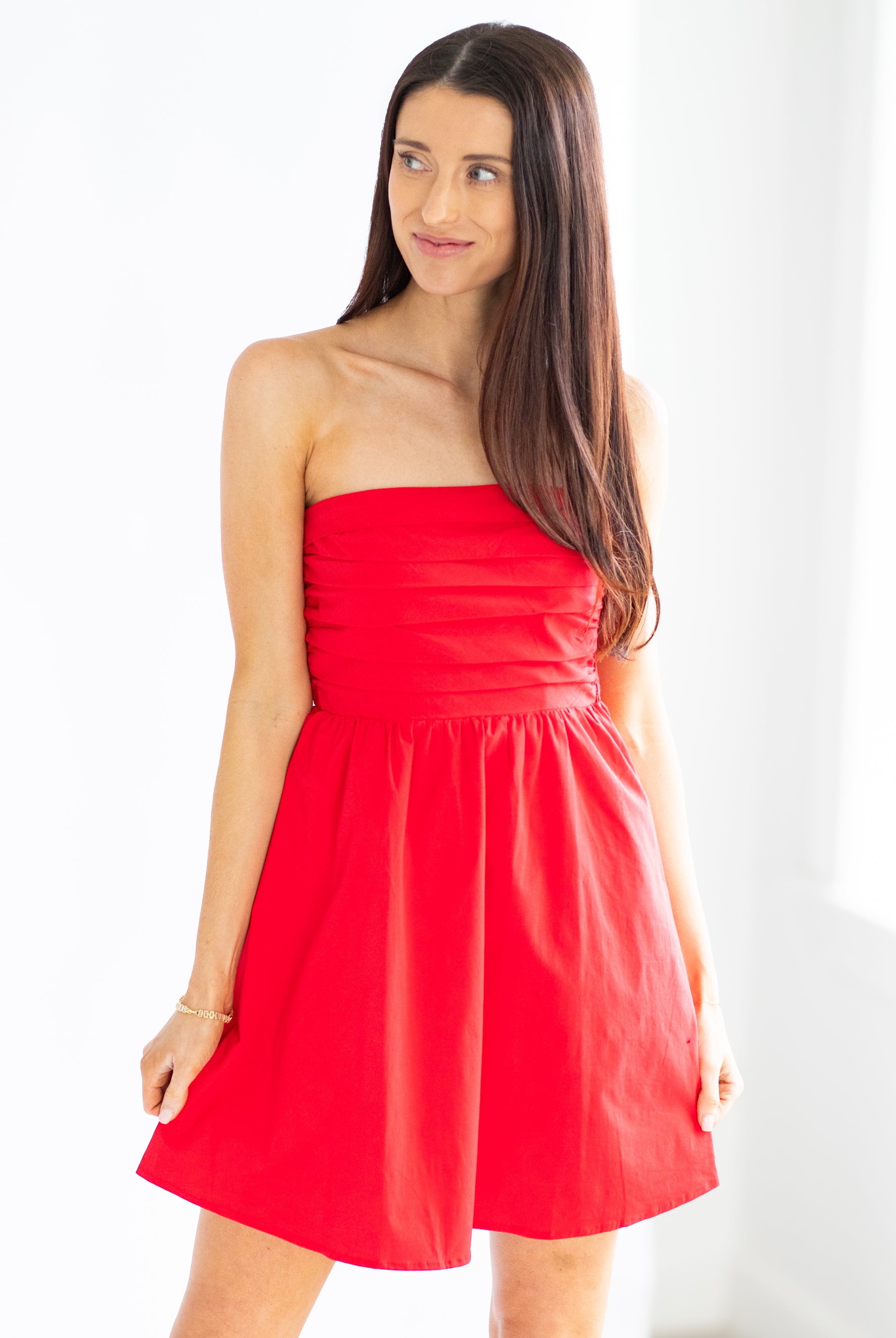 Woman wearing a strapless red dress against a white background