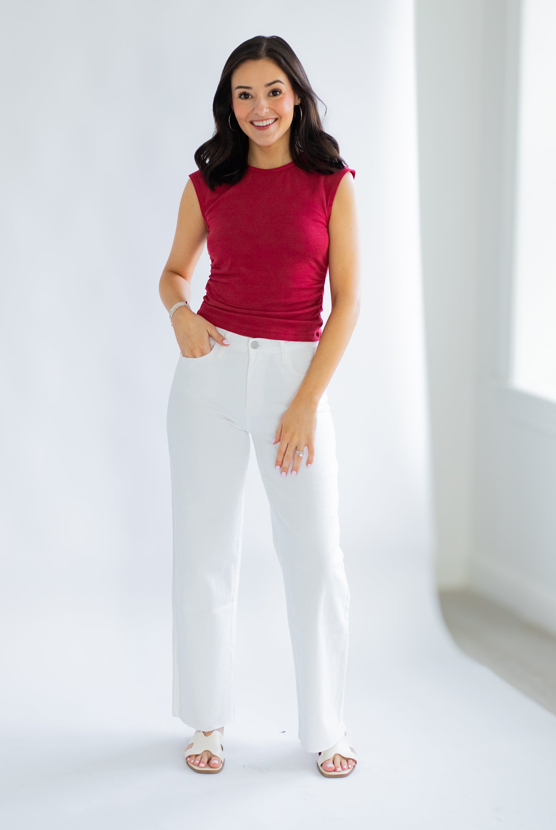 Woman wearing a red top and white pants on a white background