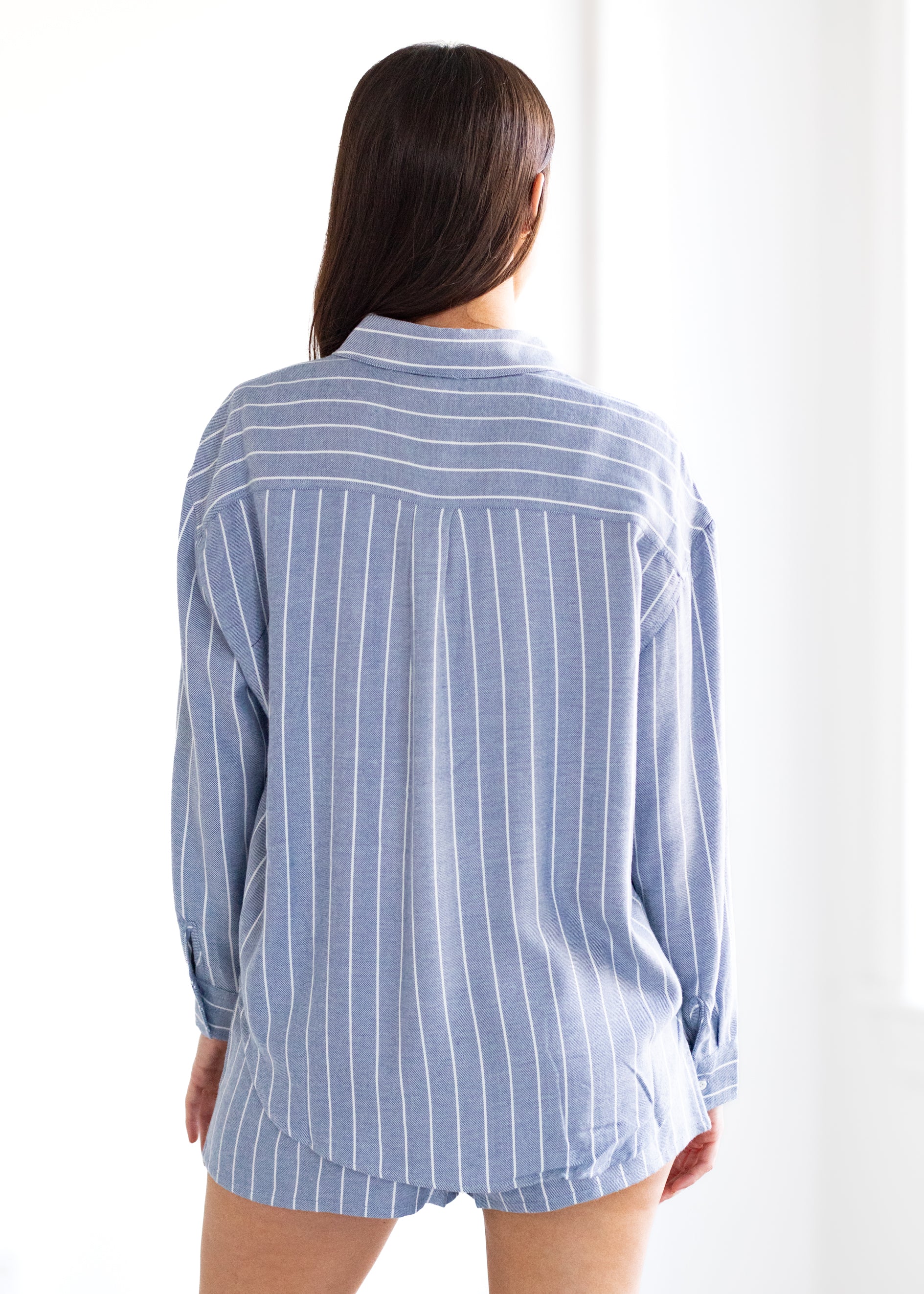Person wearing a blue and white striped shirt against a white background