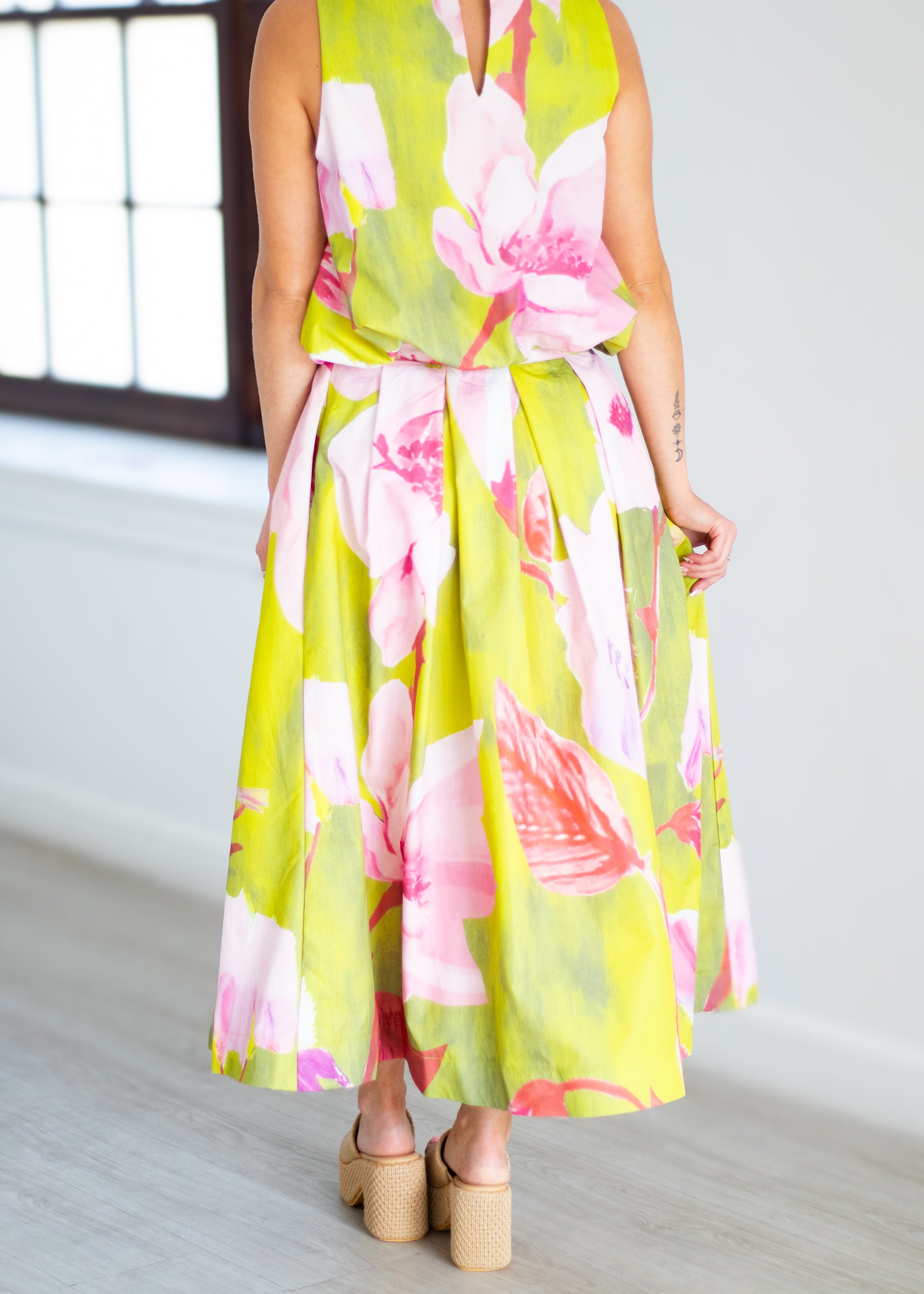 Woman wearing a floral dress with pink and green colors on a beige background