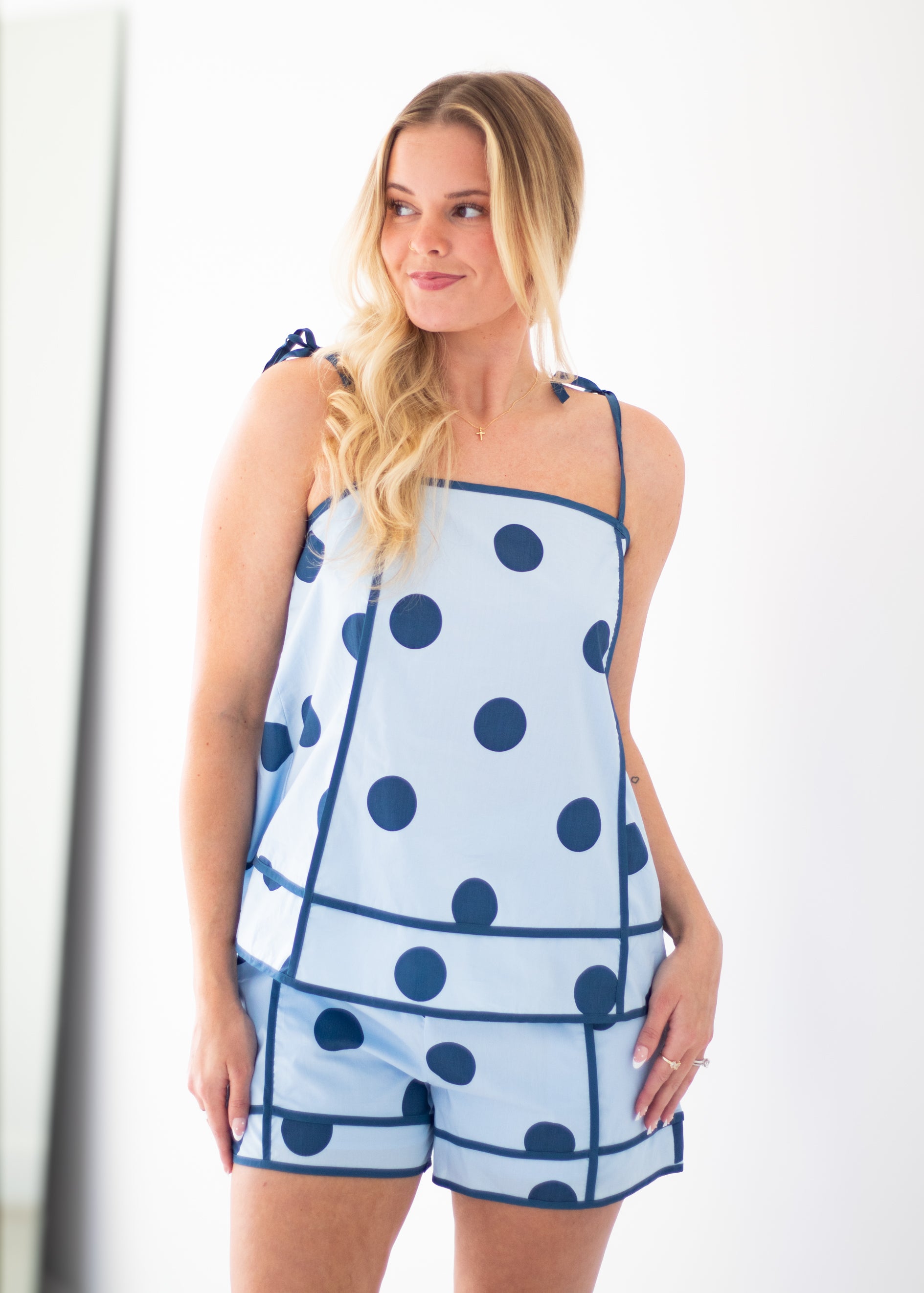 Woman wearing a blue polka dot dress against a beige background