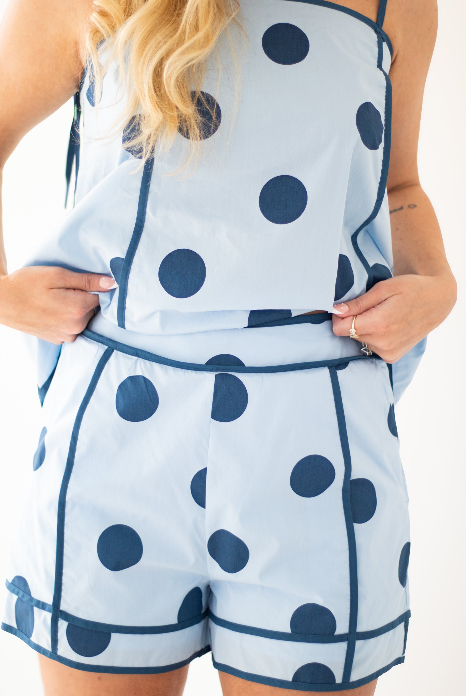 Woman wearing a blue polka dot dress against a beige background