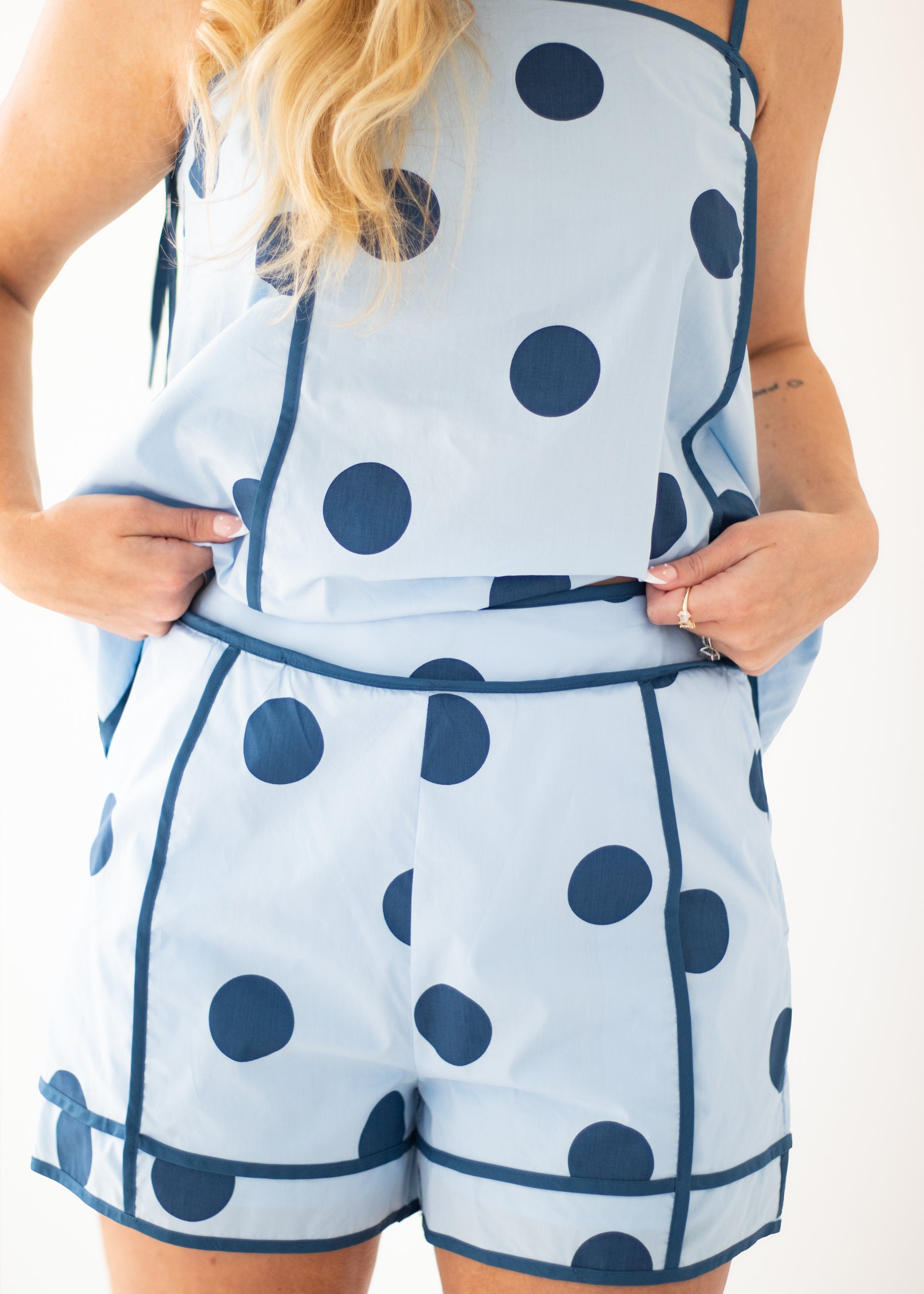 Woman wearing a blue polka dot dress against a beige background