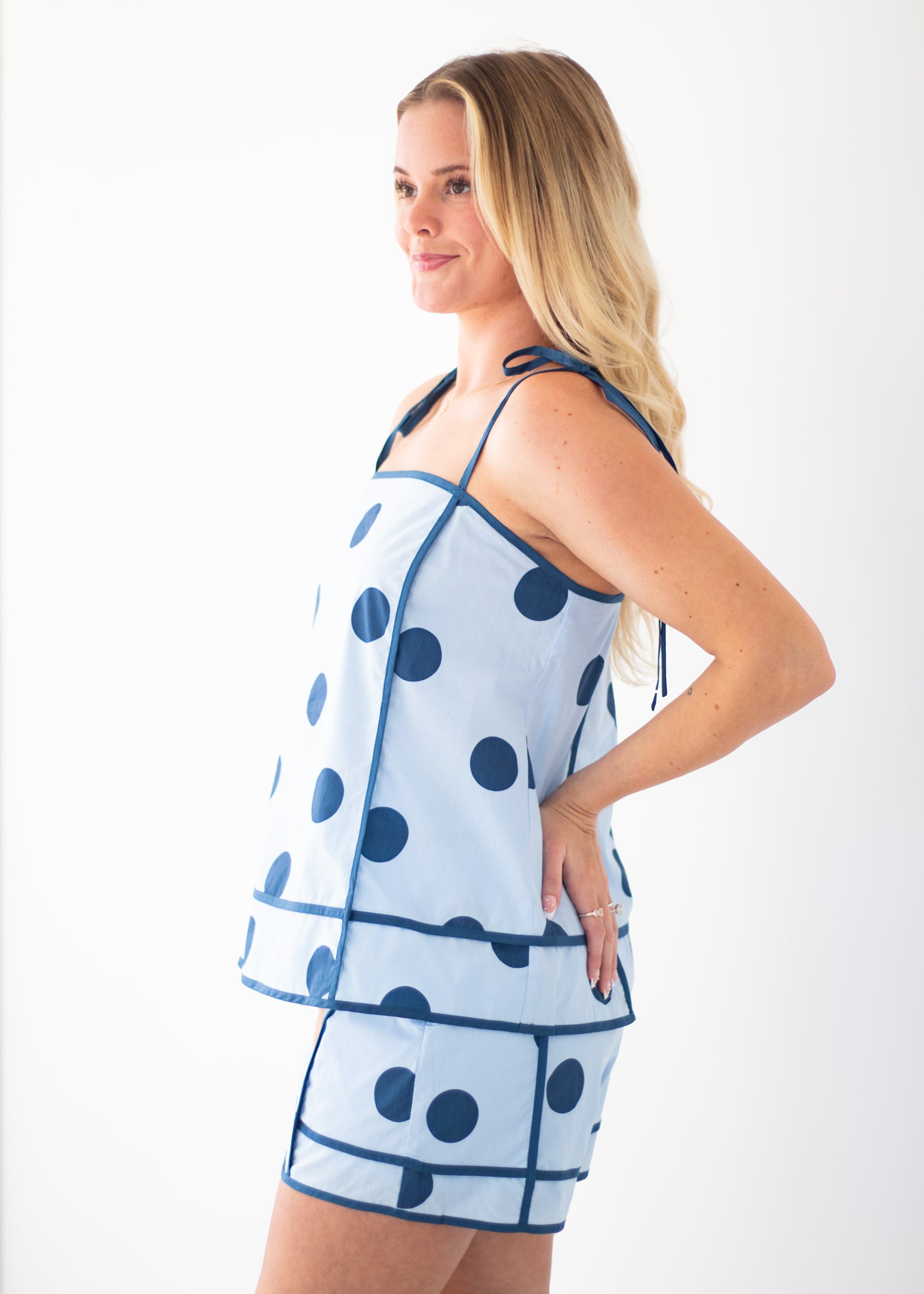 Woman wearing a blue polka dot dress against a beige background