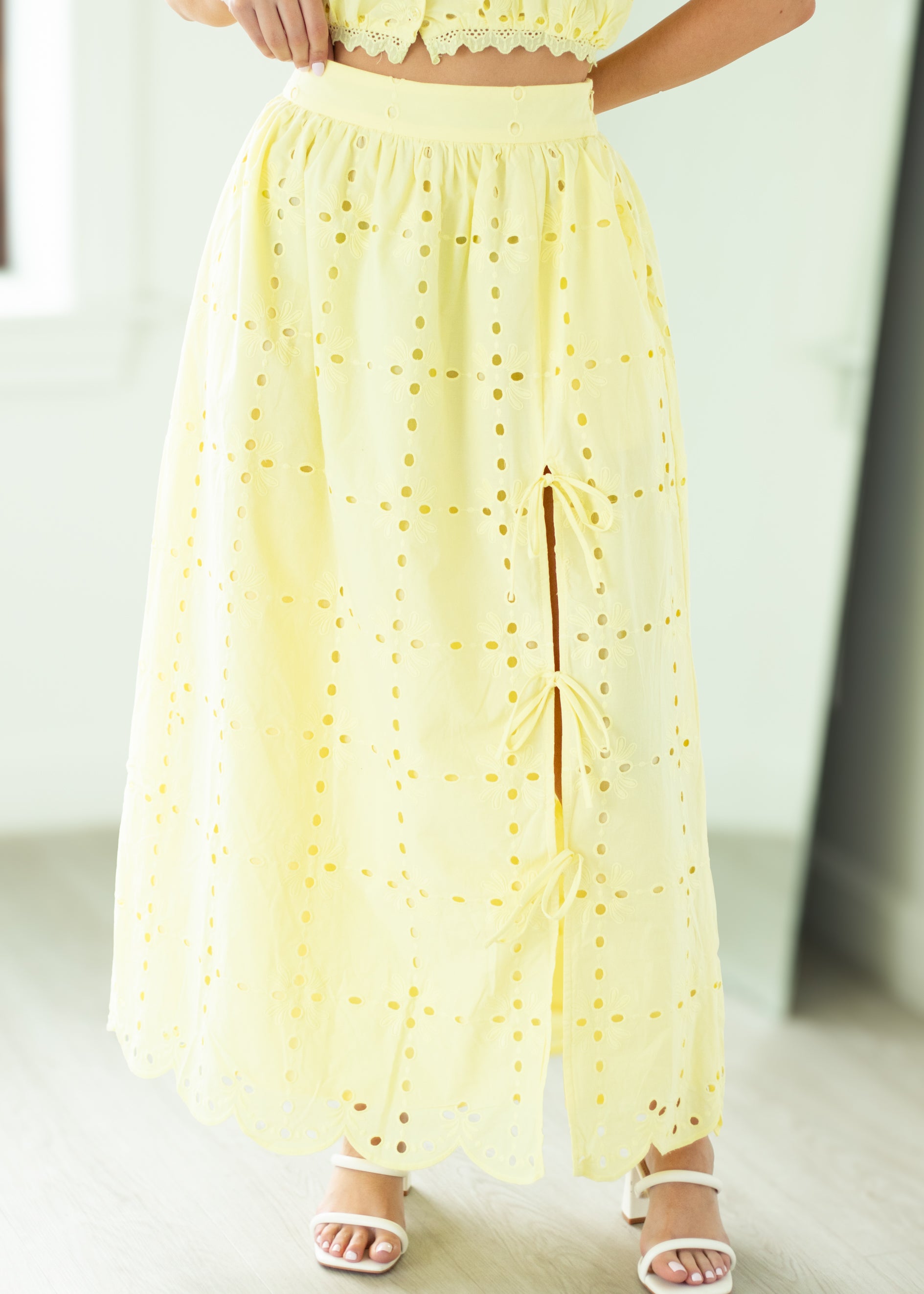 Woman wearing a yellow lace skirt standing in a bright room.