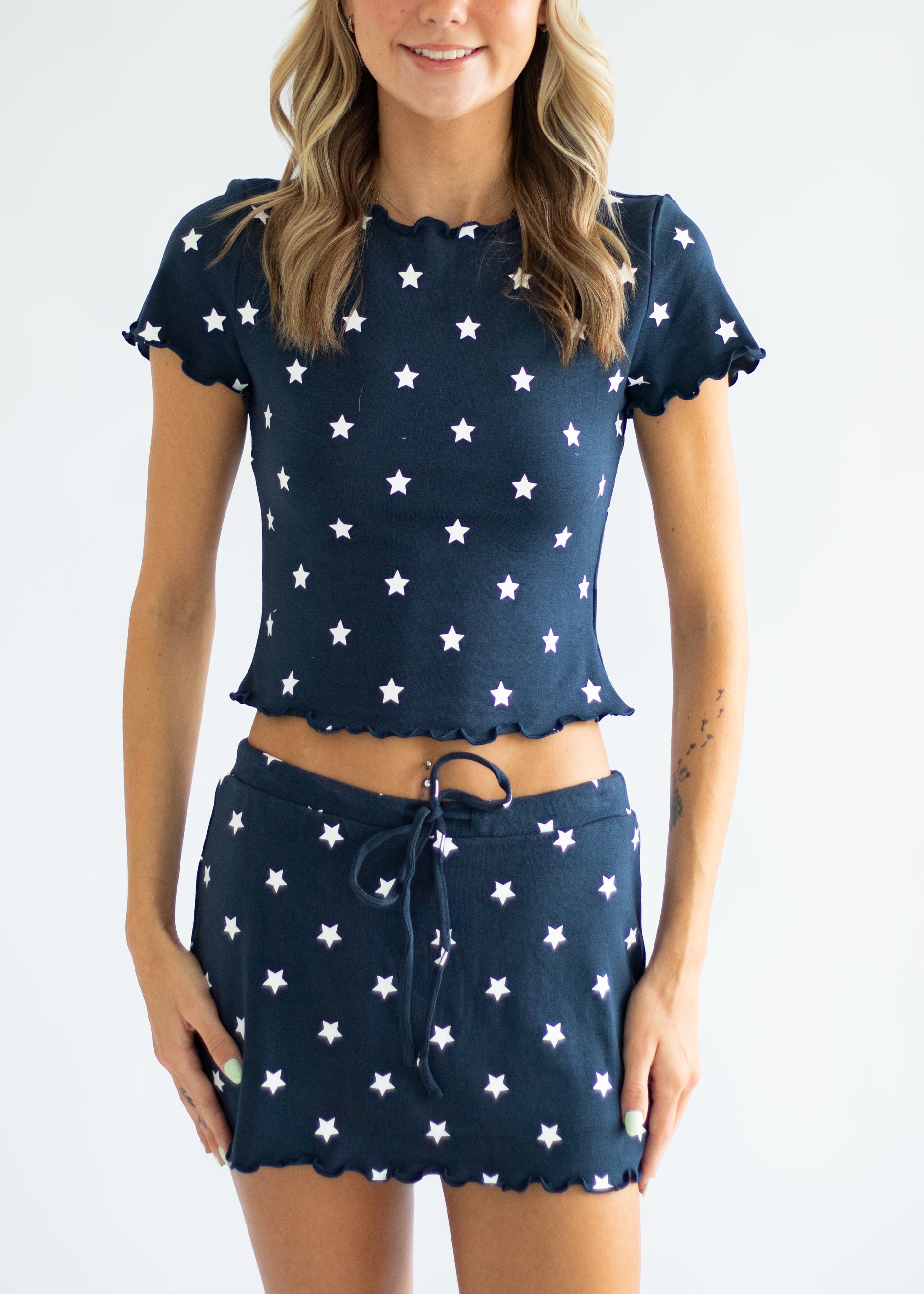 Woman wearing a navy blue outfit with white star patterns on a plain background