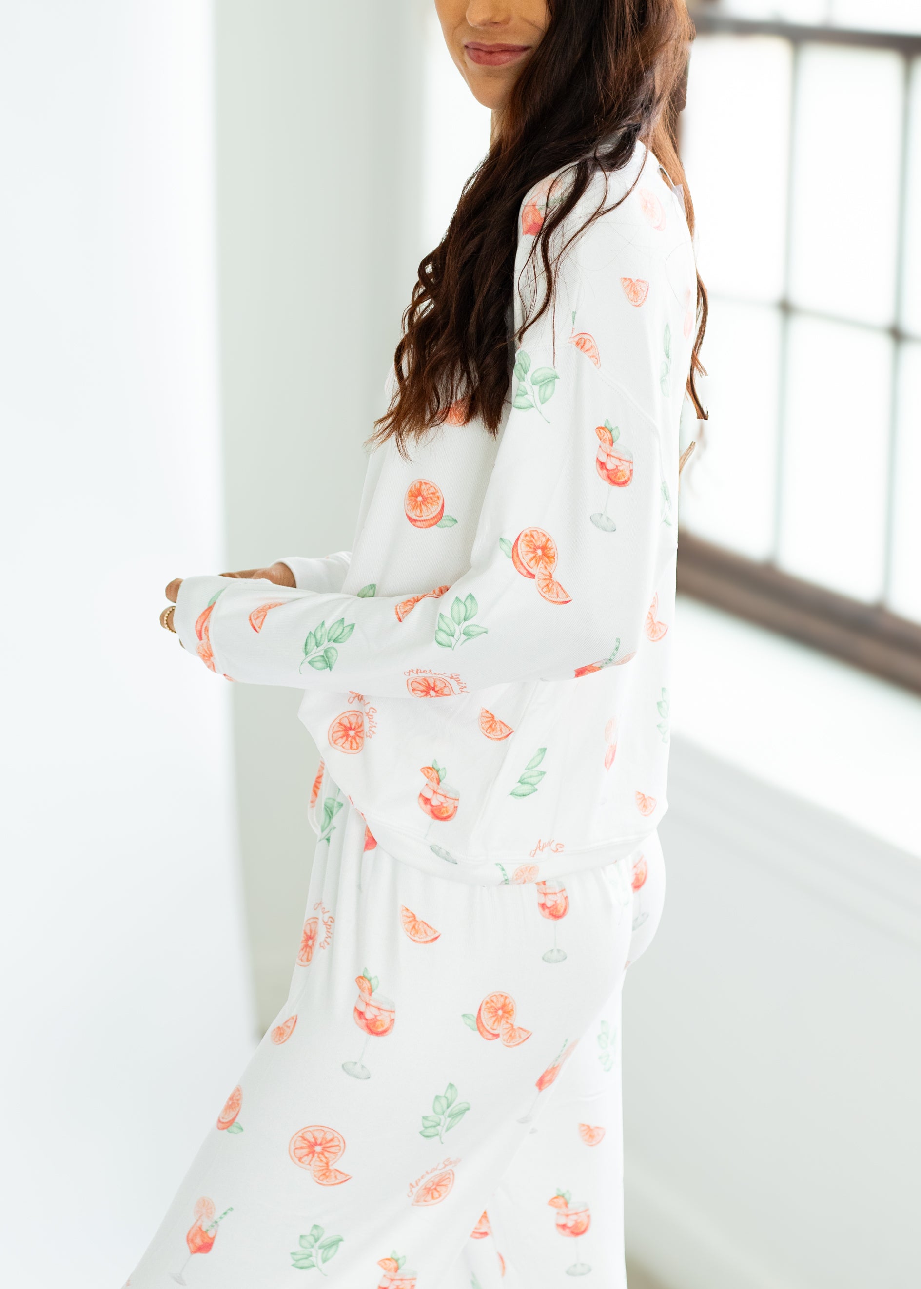 Woman wearing a white dress with floral patterns in a bright room.