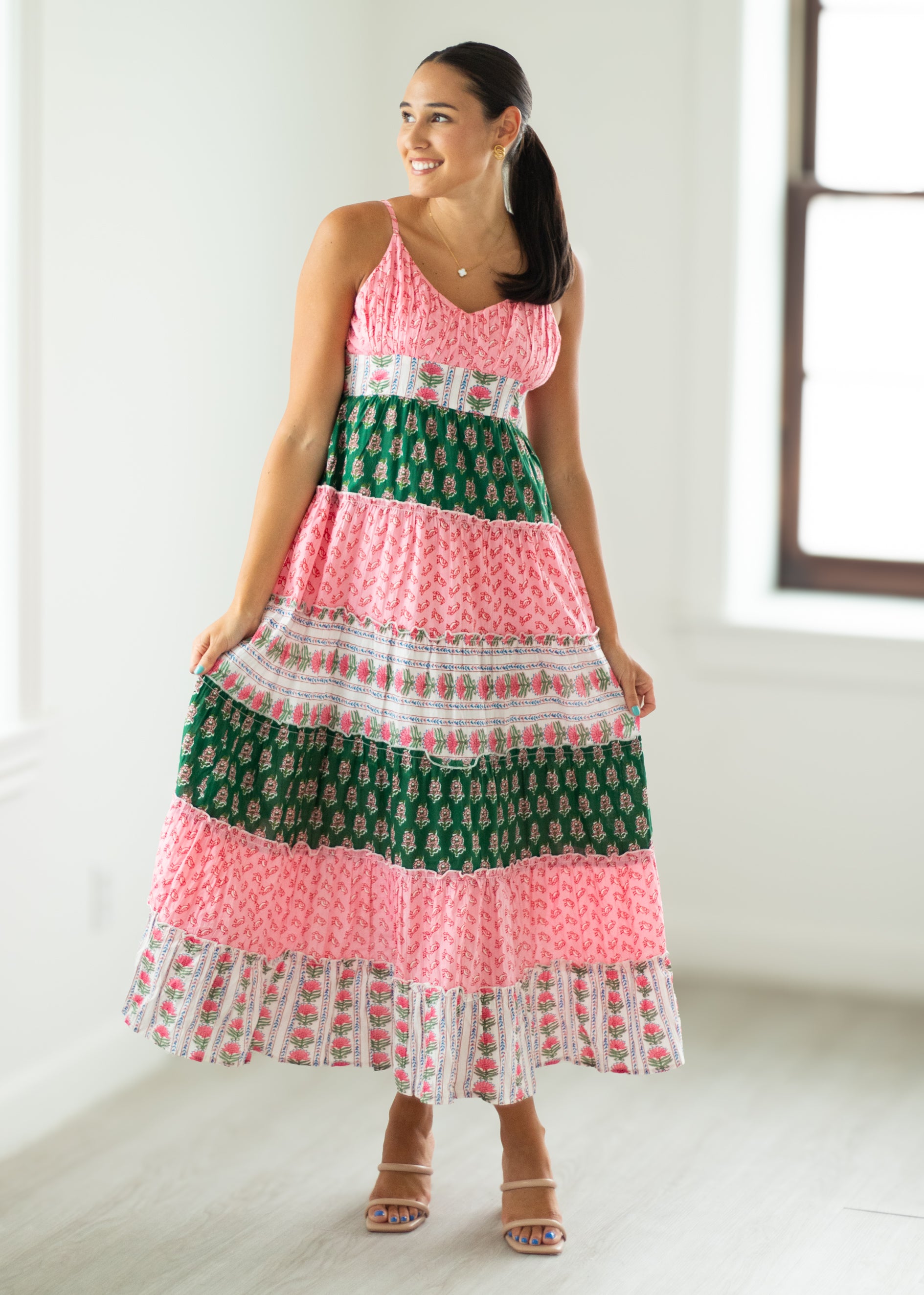 Woman wearing a colorful patterned dress in a bright room.