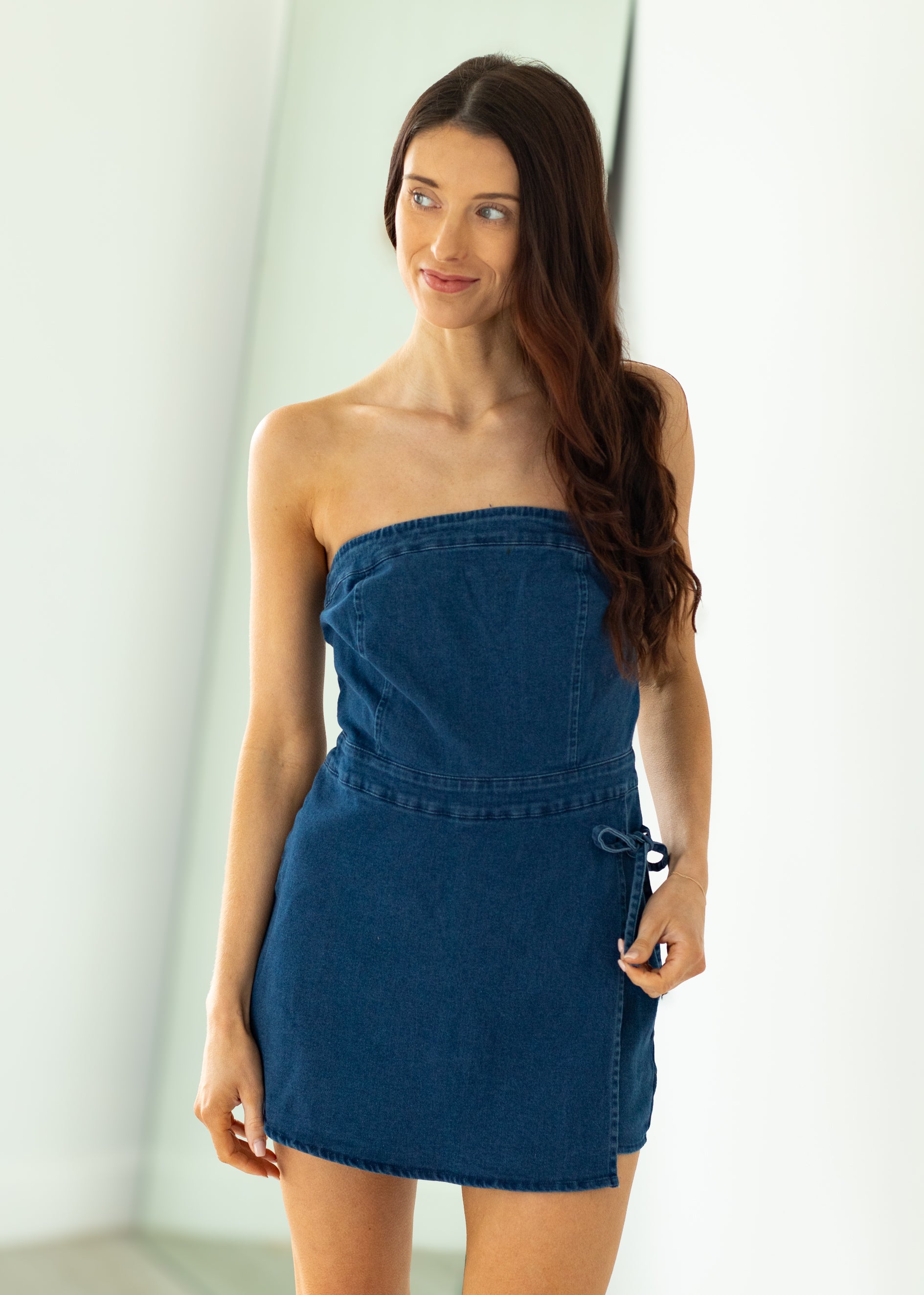 Woman wearing a blue strapless dress against a white background