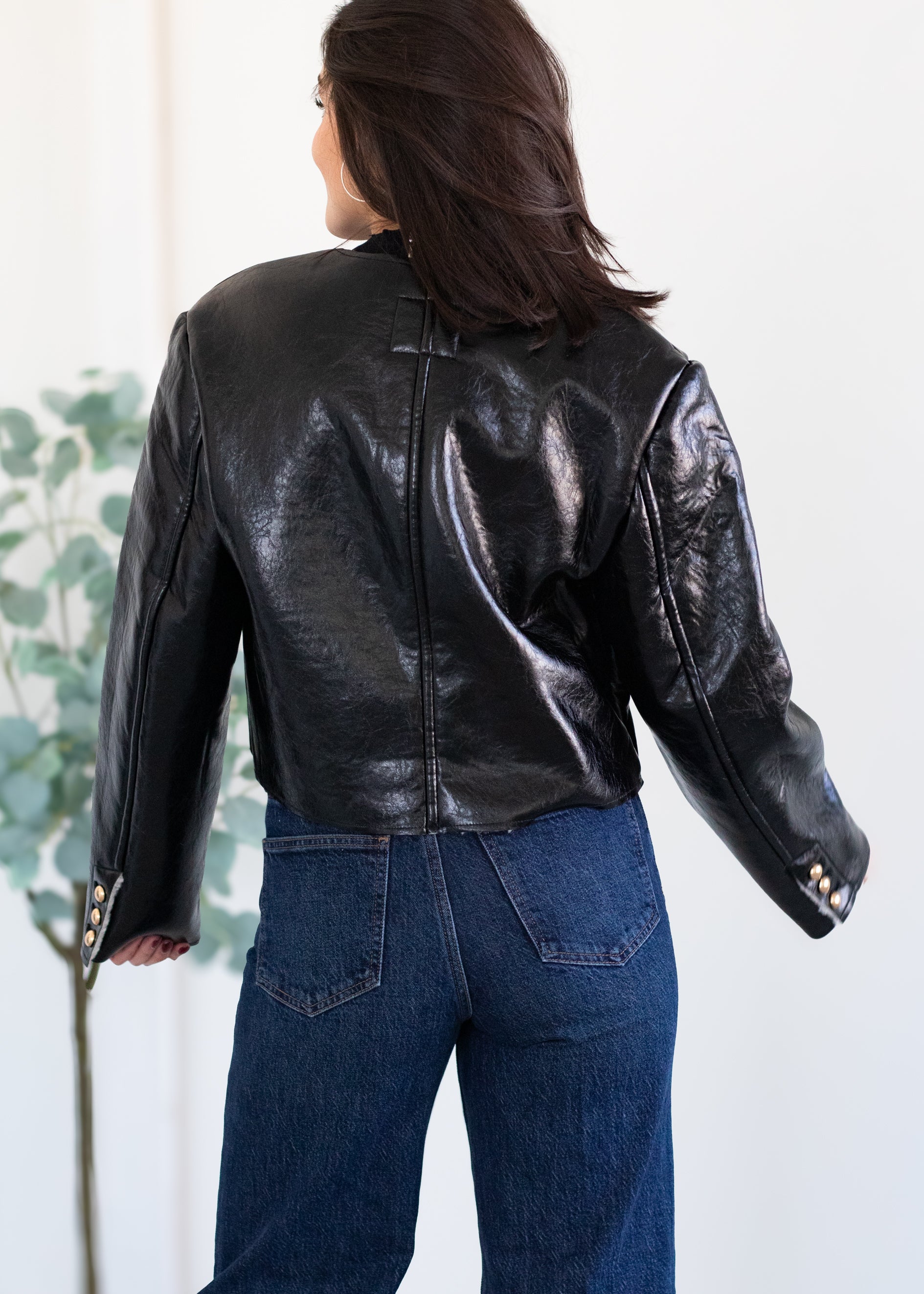 Person wearing a black leather jacket and blue jeans against a white background