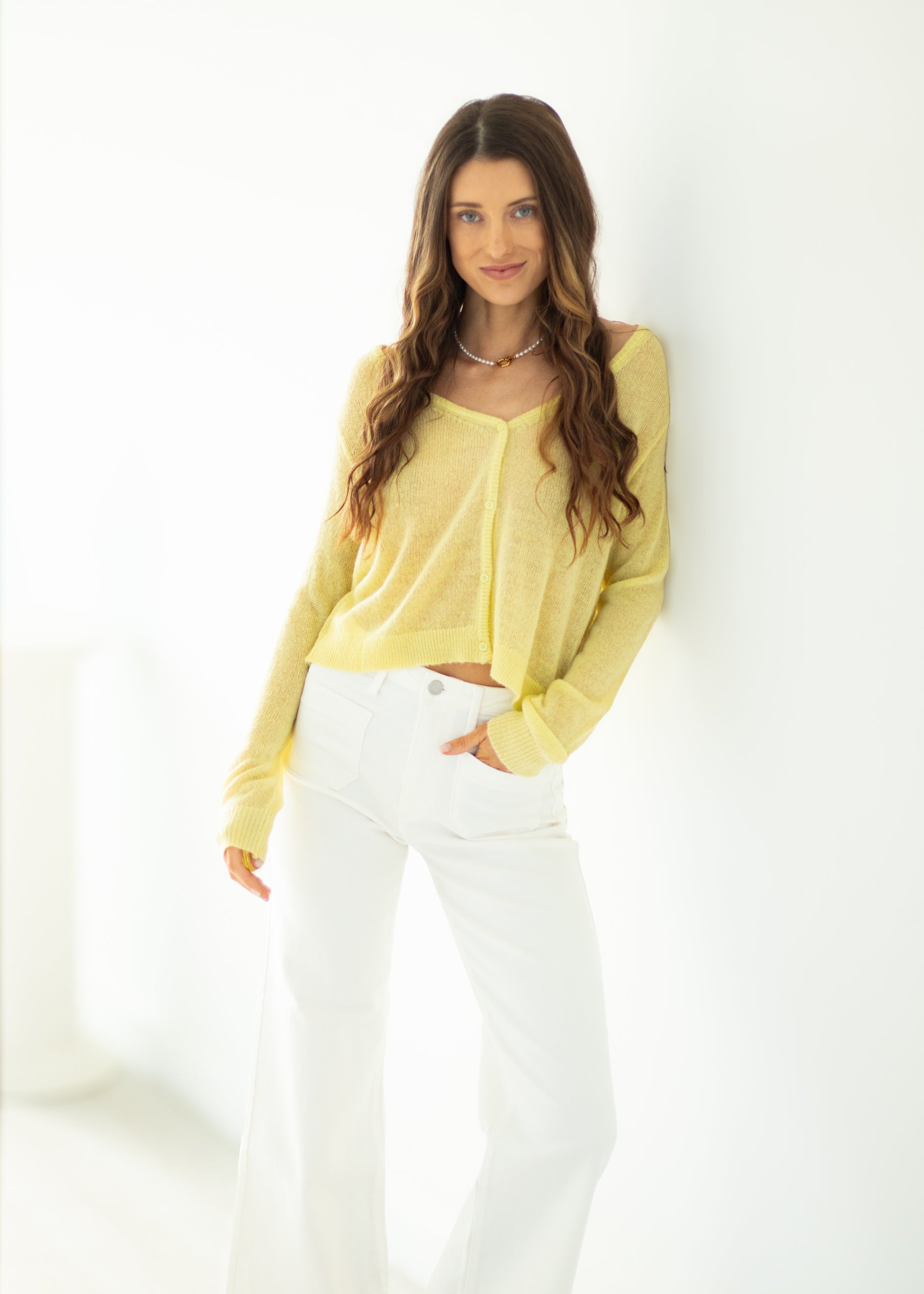 Woman wearing a yellow top and white pants against a white background