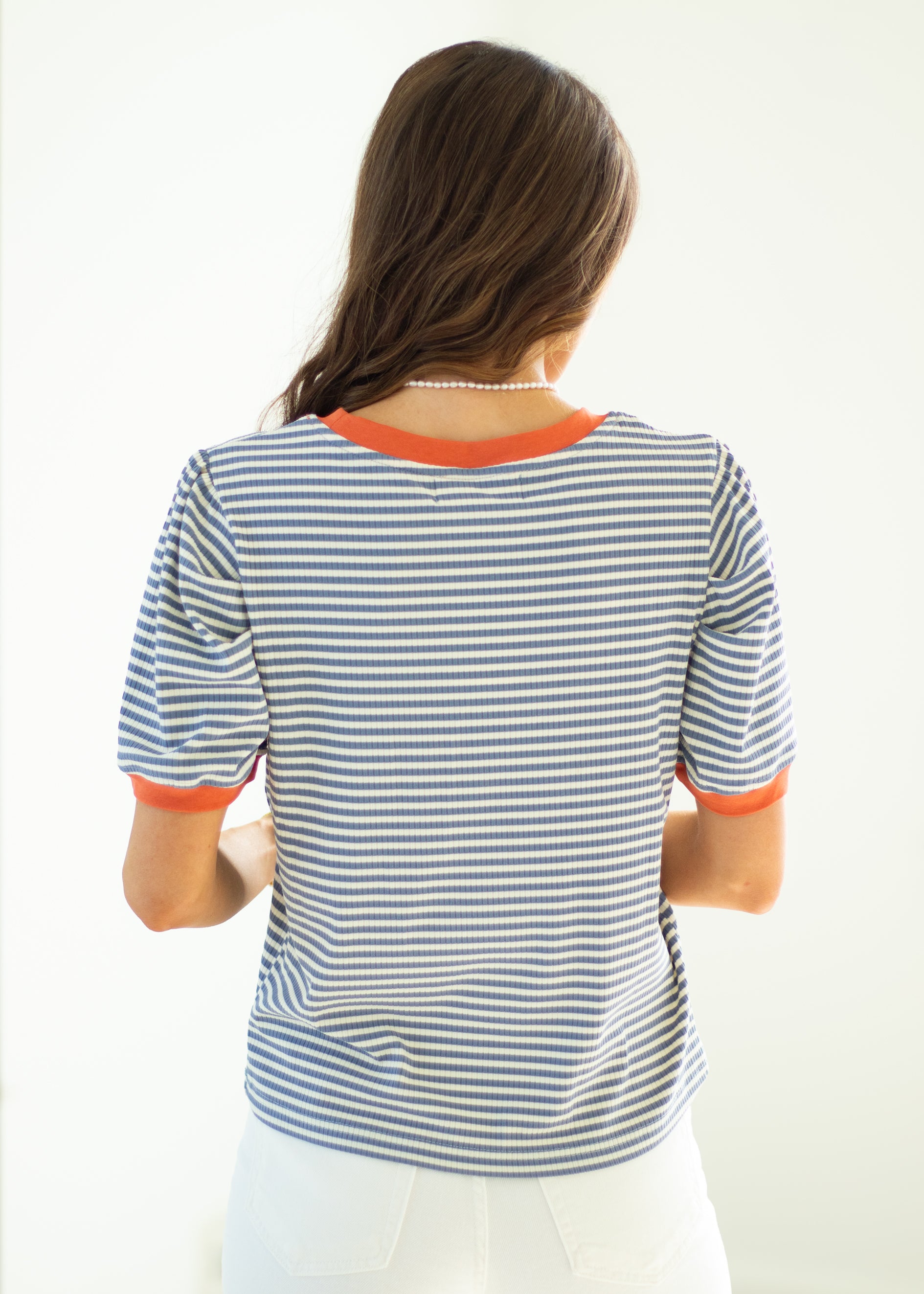 Woman wearing a striped shirt with orange trim on a white background