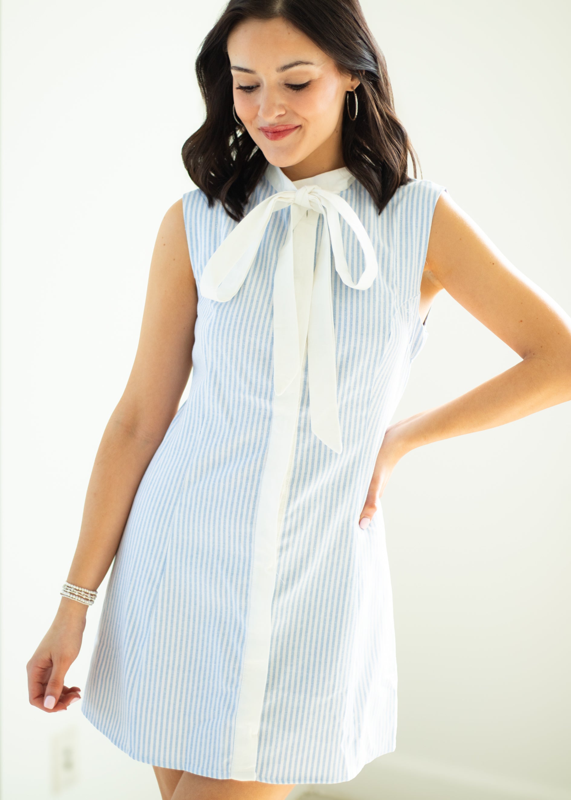 Woman wearing a blue and white striped dress with a bow tie on a white background