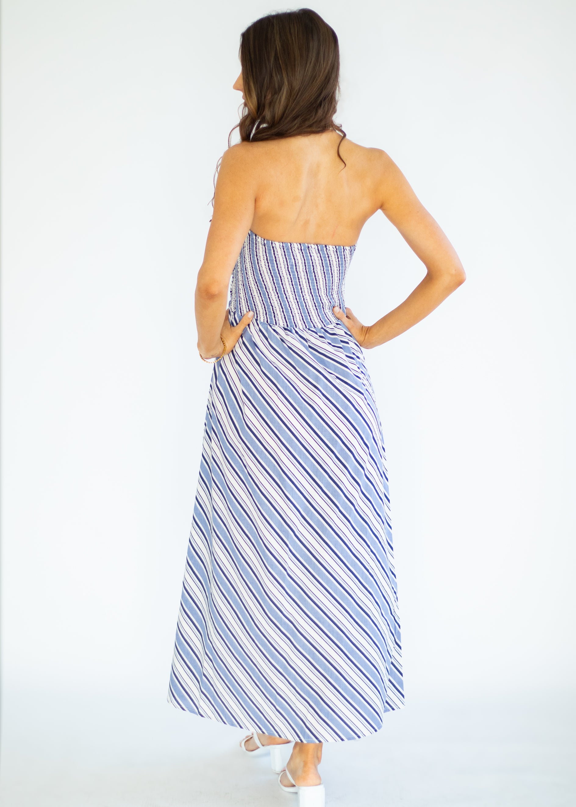 Woman wearing a blue and white striped dress against a white background