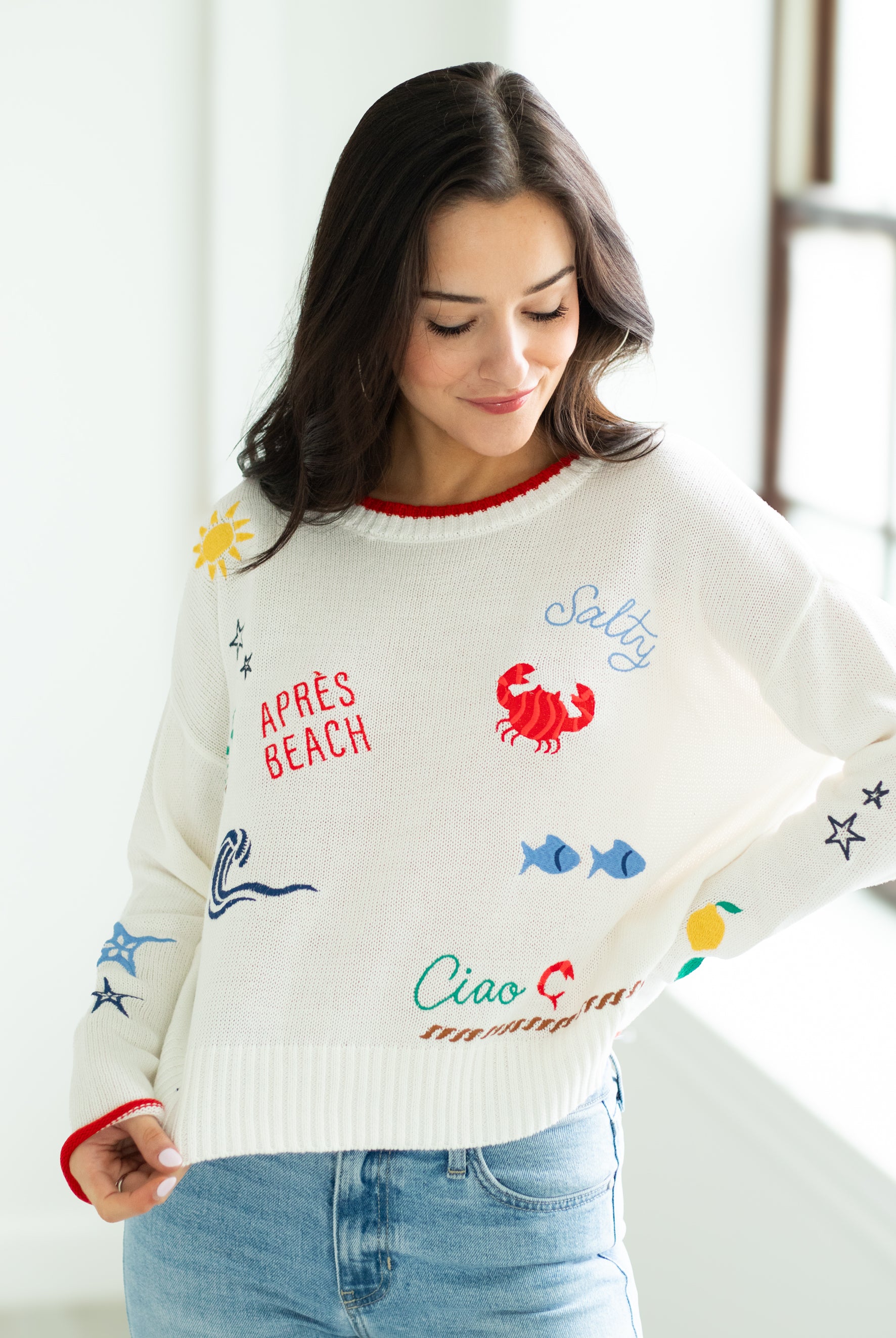 Woman wearing a white sweater with colorful graphics and text